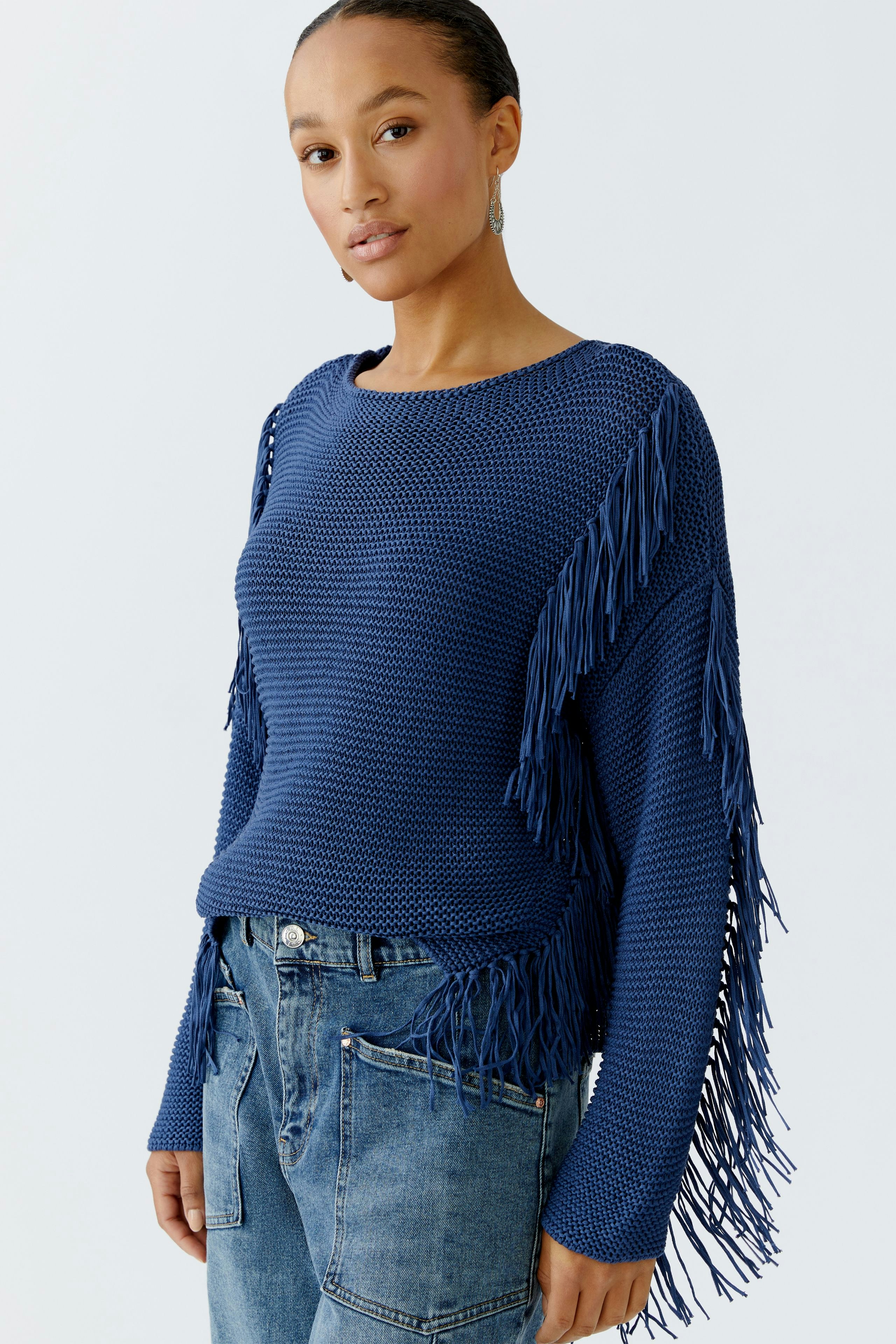 Damen-Pullover in Blau mit Fransen, lässig kombiniert mit Jeans, Model mit kurzen Haaren.
