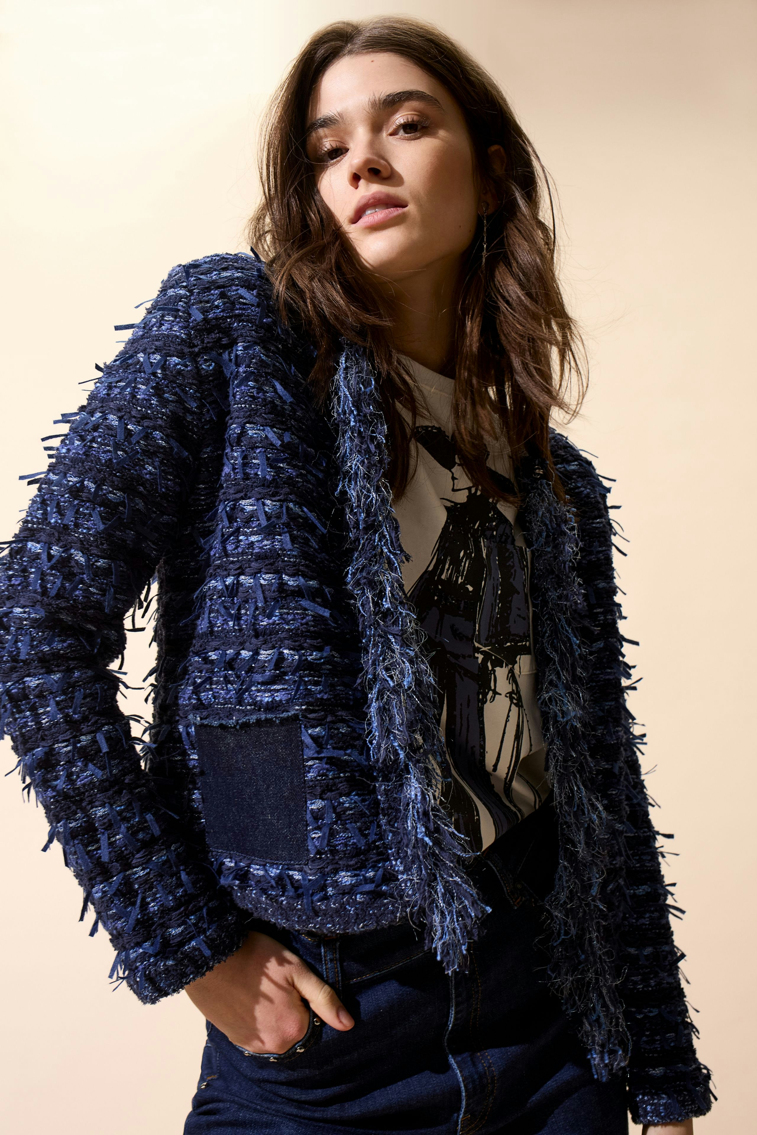 Casual women's cardigan: Young woman in a textured navy cardigan with a graphic tee and denim.