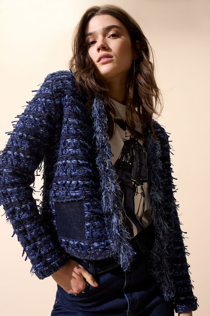 Damen-Strickjacke: Junge Frau in blauer Strickjacke mit fransigen Details und lässigem Shirt.
