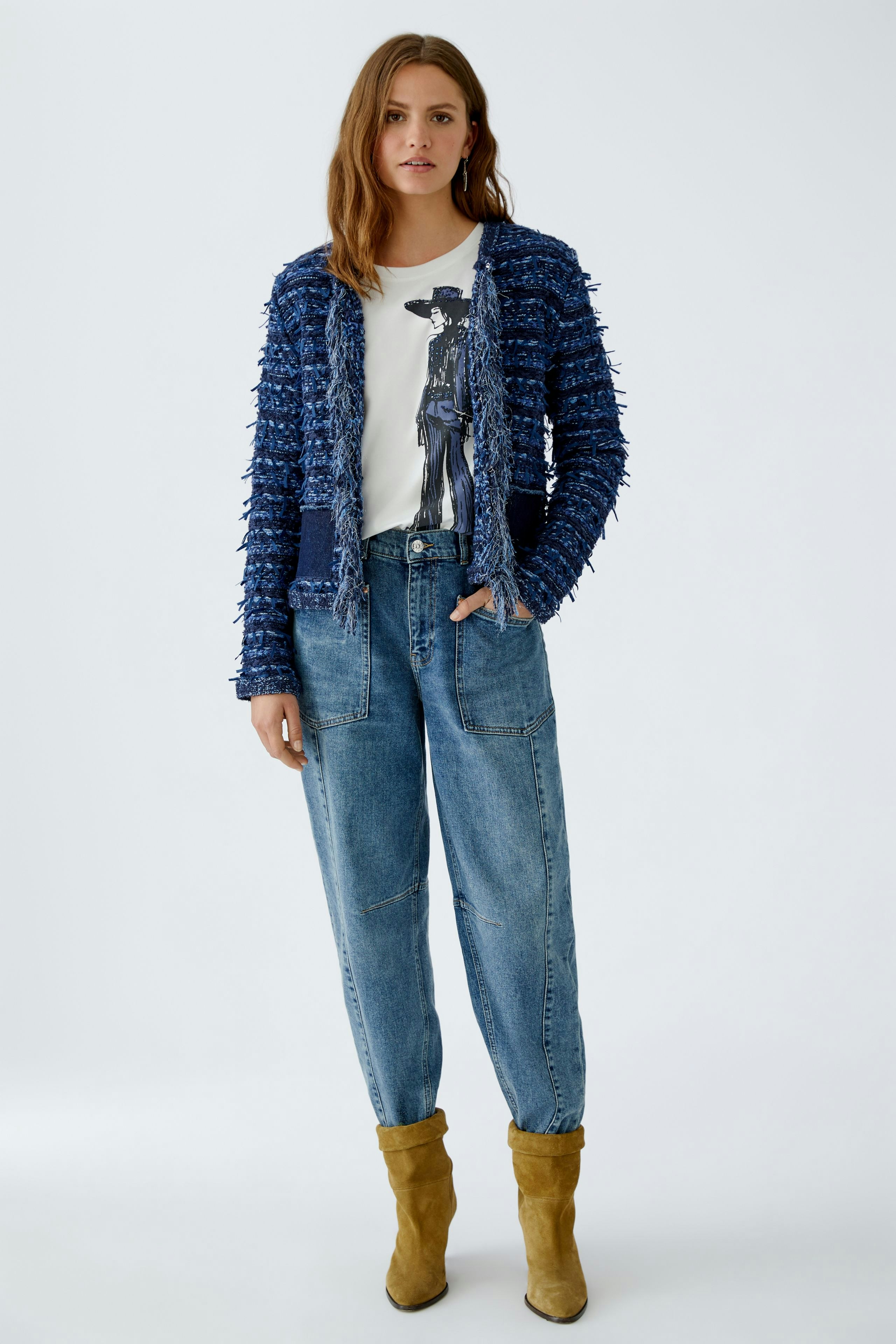 Casual women's cardigan: A woman in a textured blue cardigan over a graphic tee and relaxed jeans.