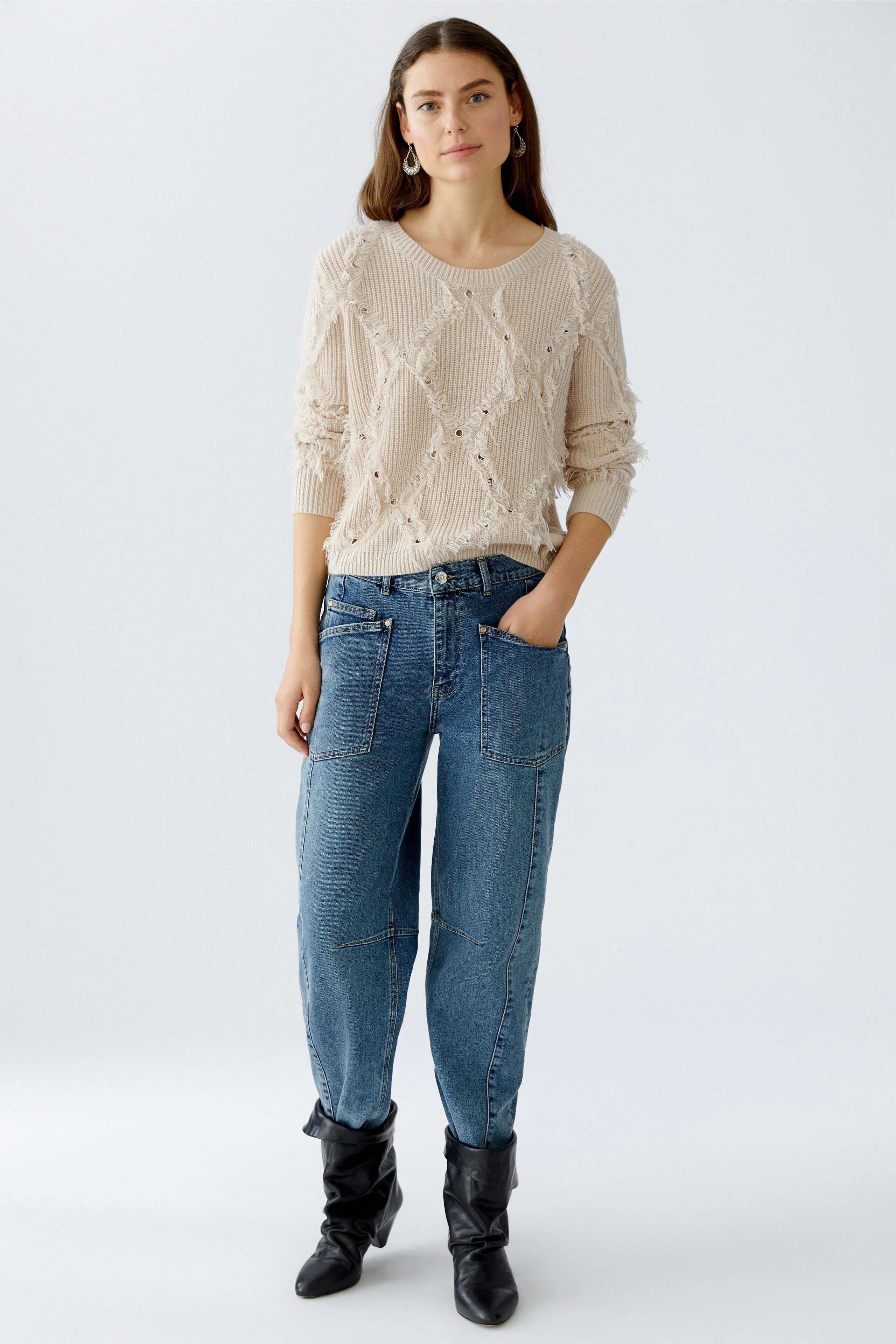 Casual women's pullover: Young woman in a light beige knitted pullover with textured details.