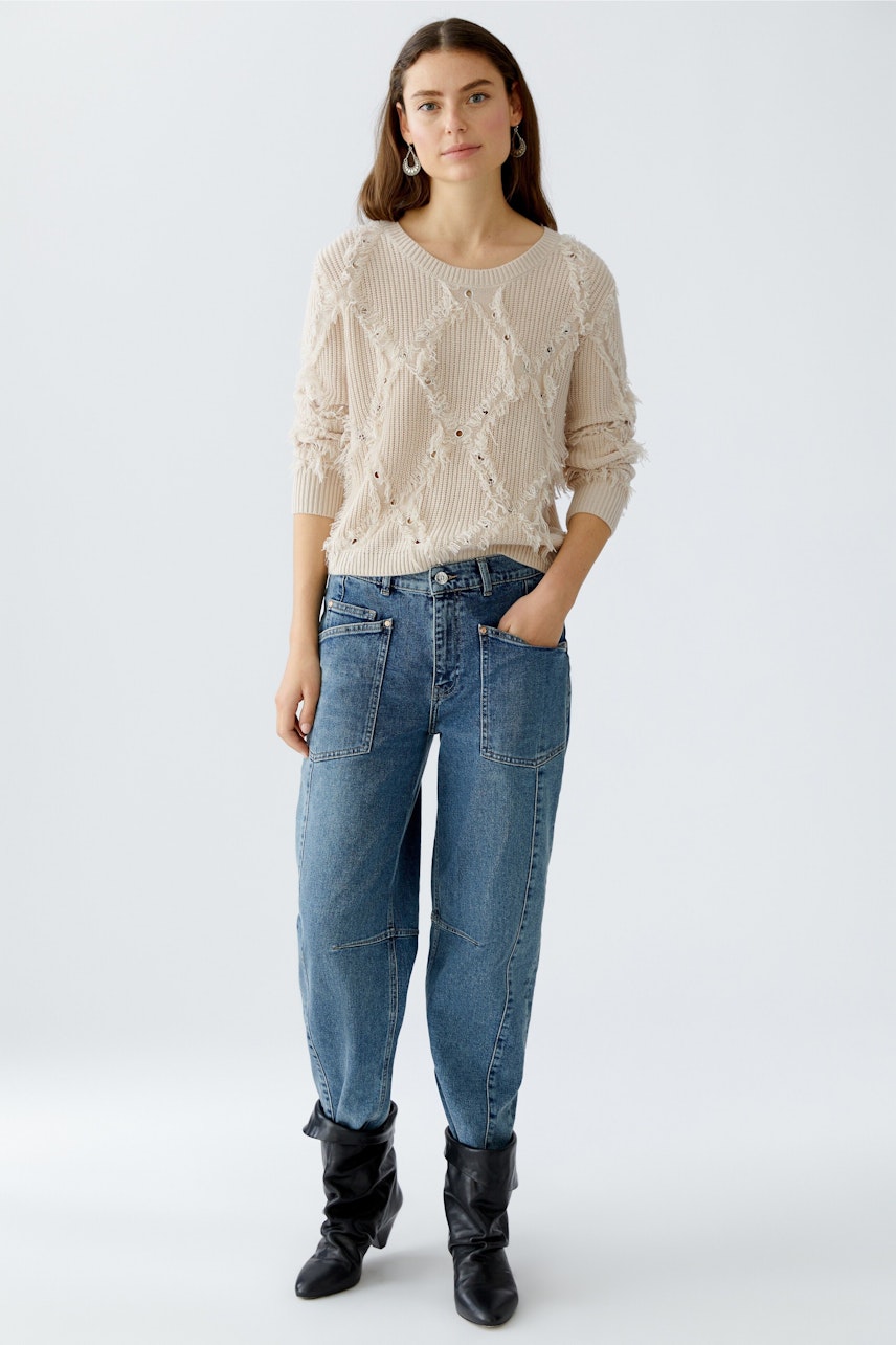 Beiger Damen-Pullover mit strukturiertem Design, lässig kombiniert mit Jeans und Stiefeln.