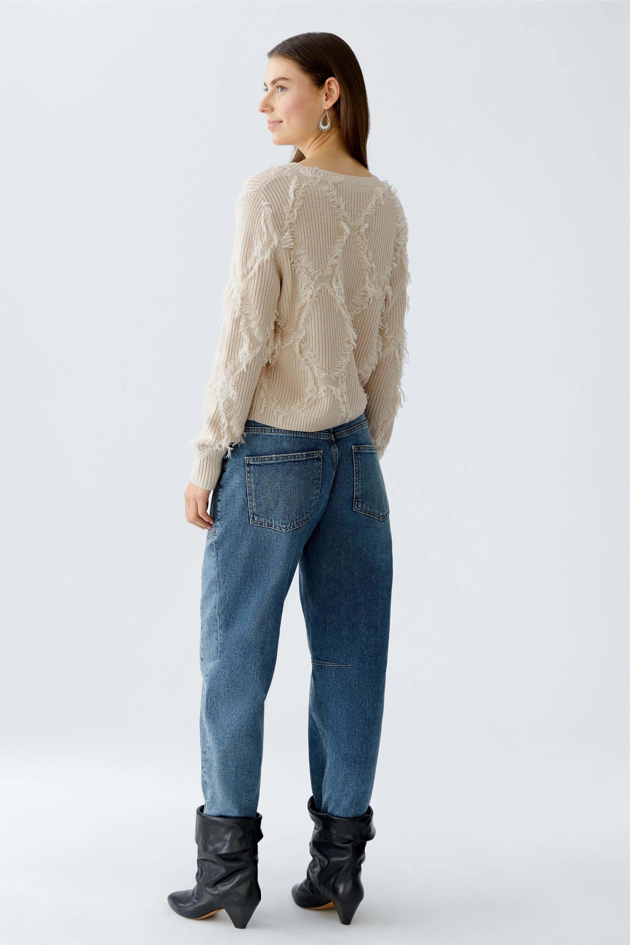 Casual women's pullover: A woman in a beige textured pullover paired with relaxed jeans.