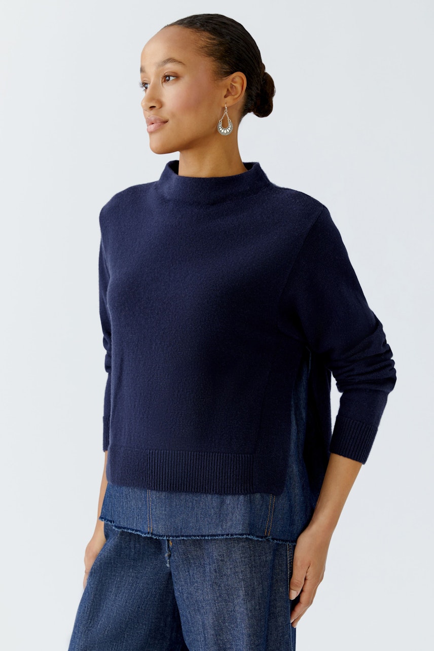 Damen-Pullover: Frau in dunkelblauem Pullover mit Stehkragen und lässigem Schnitt.