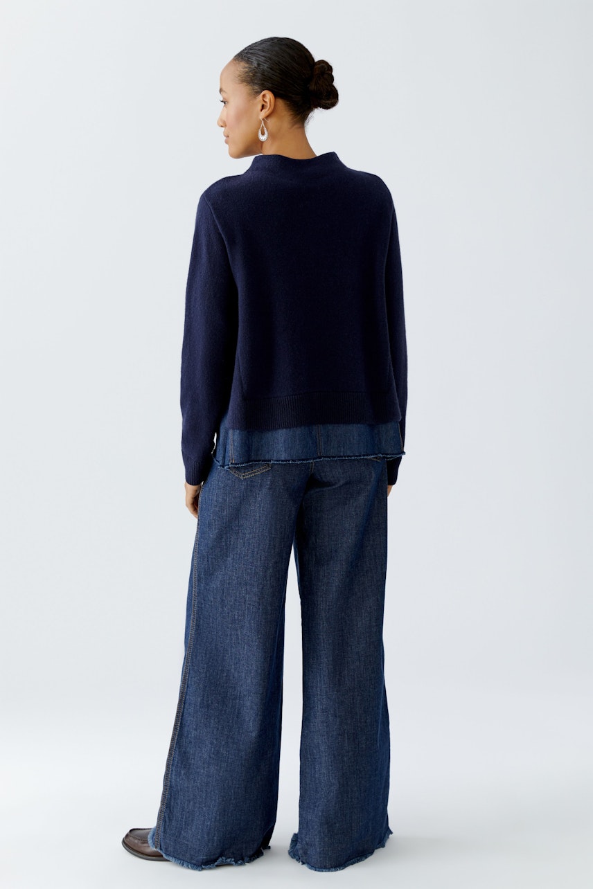 Damen-Pullover: Frau in dunkelblauem Pullover mit lässigem Schnitt und weitem Denim-Hosen.