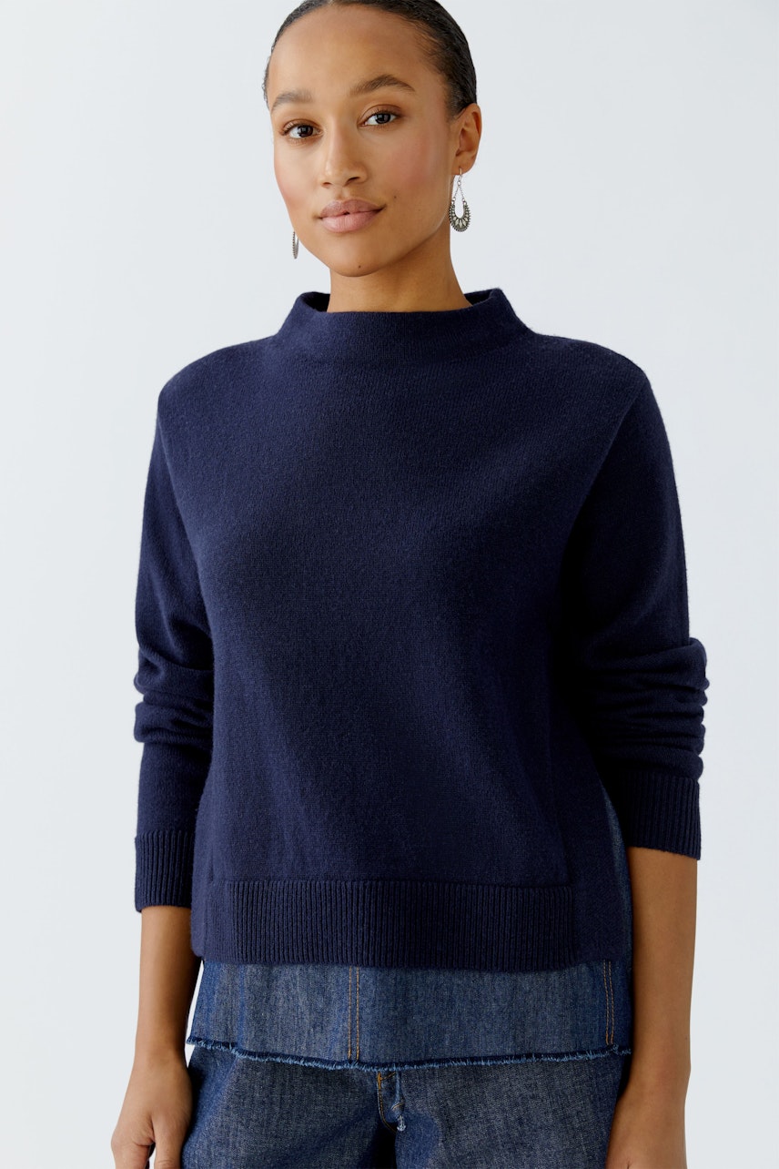 Damen-Pullover: Frau in dunkelblauem Pullover mit hohem Kragen und lässigem Schnitt.
