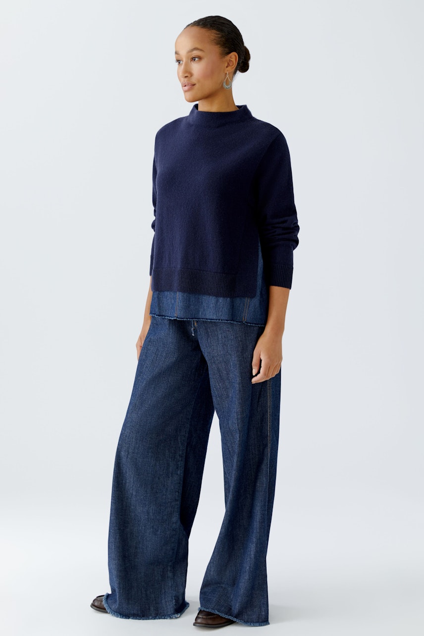 Damen-Pullover: Frau in dunkelblauem Pullover mit lässigem Schnitt und weiten Jeans.