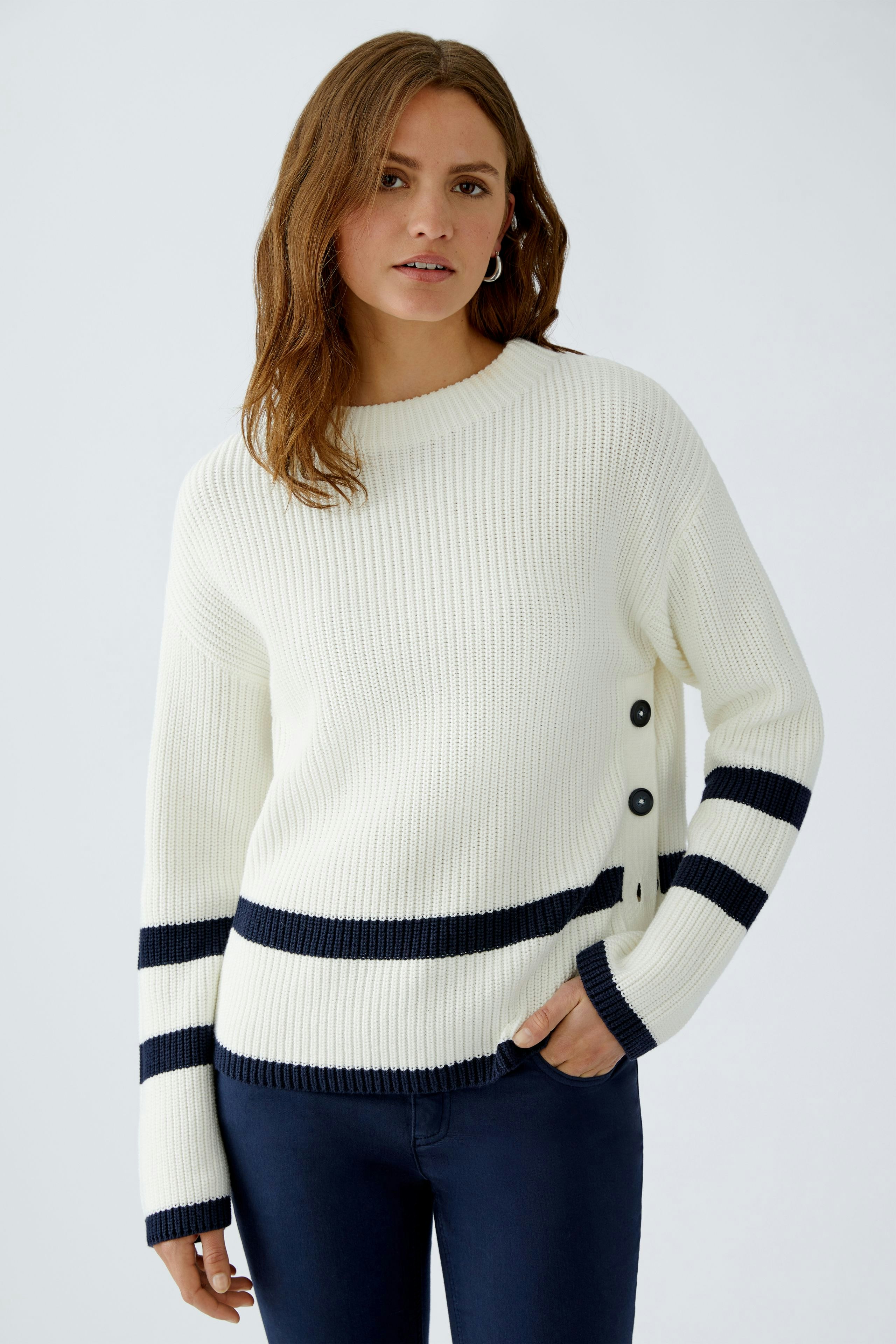 Casual women's pullover: Young woman in a white ribbed pullover with navy stripes and button details.