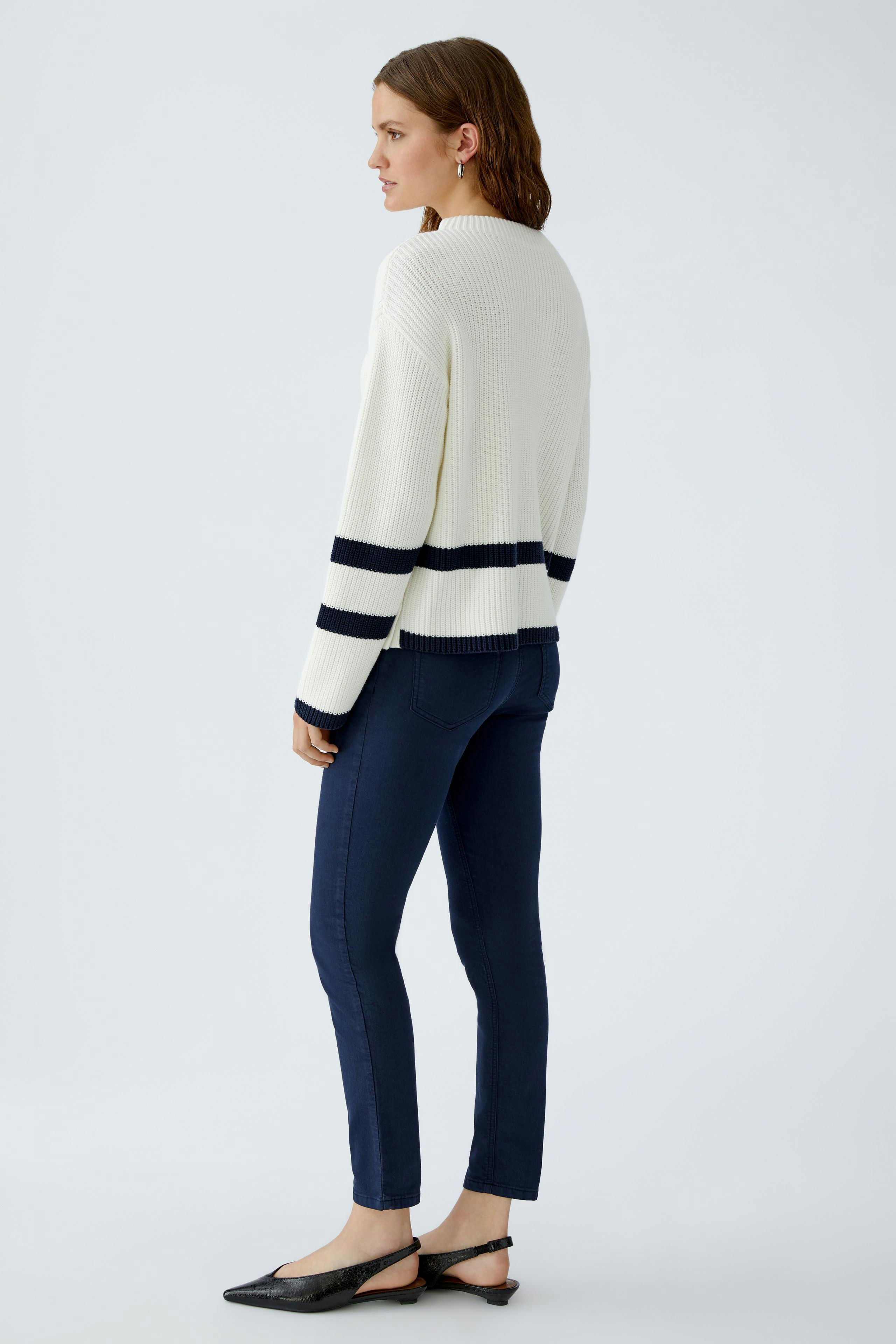 Casual women's pullover: A woman in a white ribbed pullover with navy stripes and fitted jeans.