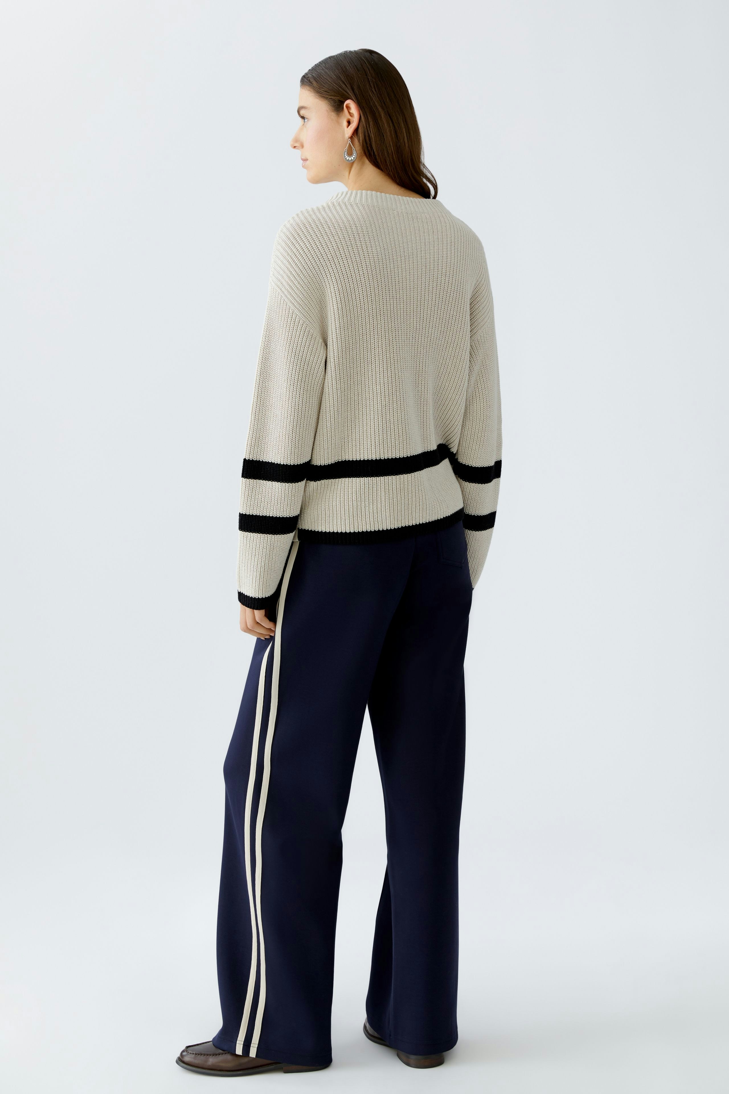 Casual women's pullover: A woman in a light gray pullover with black stripes, viewed from the back.