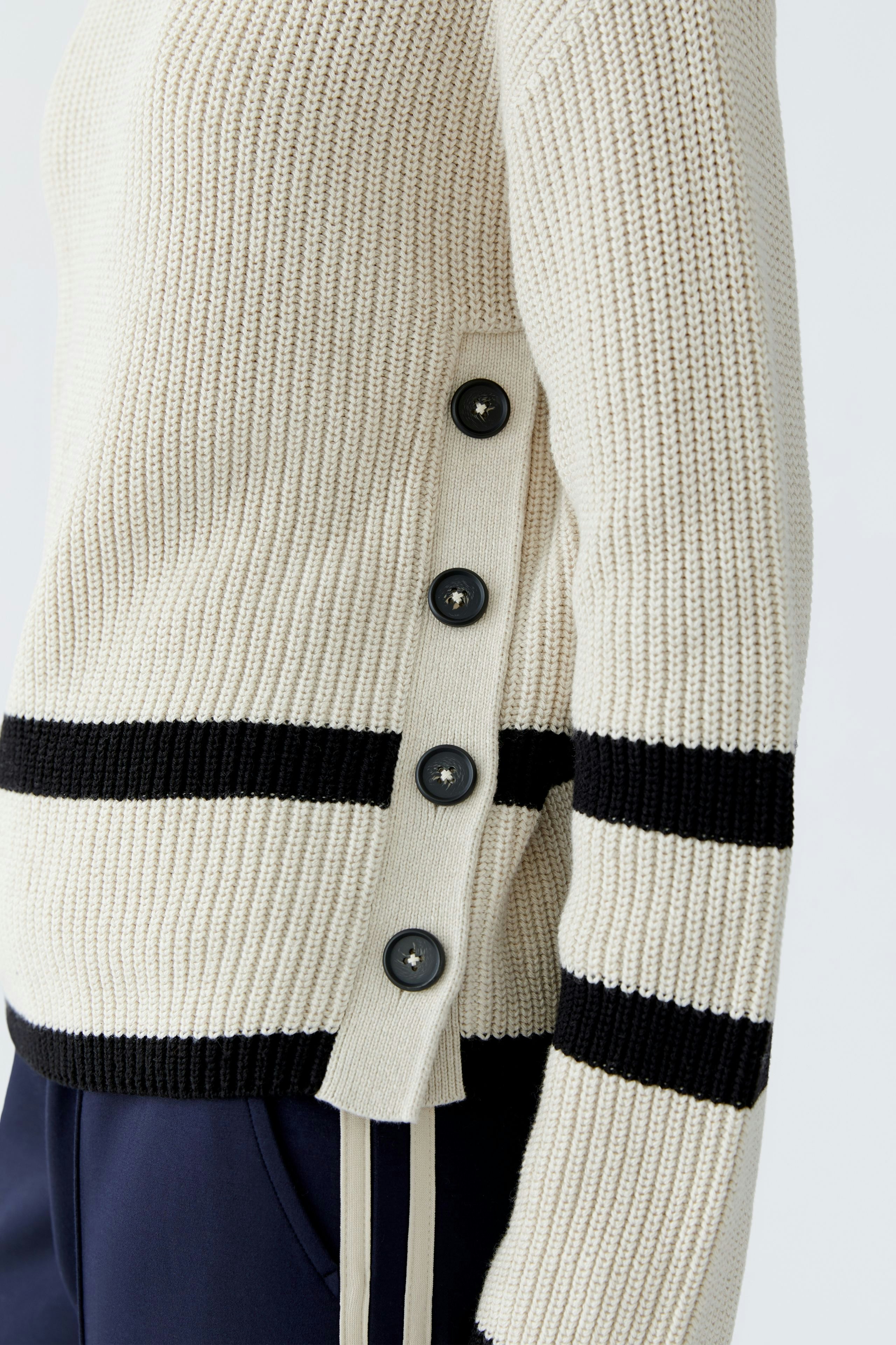 Casual women's pullover in cream with black stripes and button details on the side.
