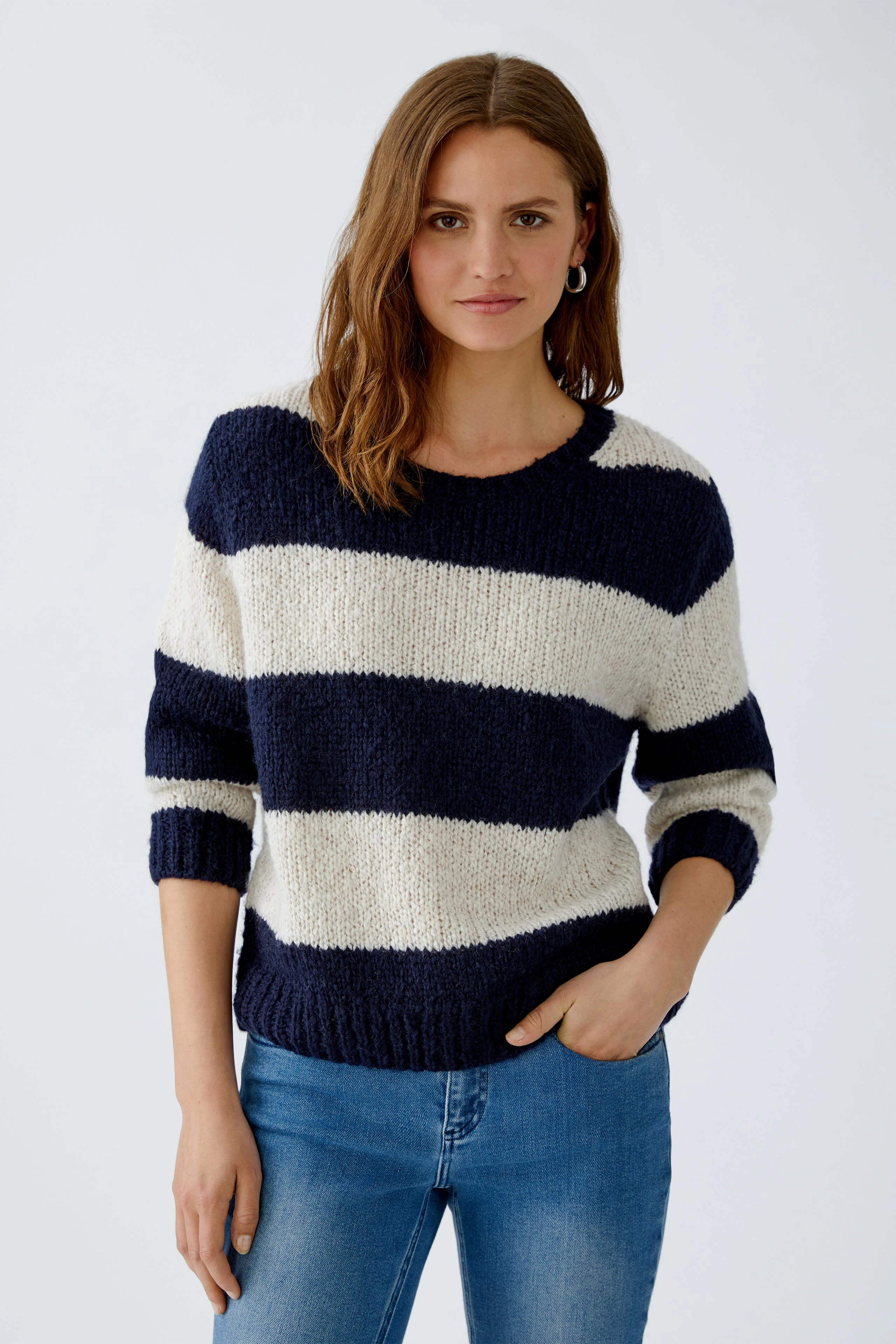 Damen-Pullover: Junge Frau in gestreiftem Pullover mit maritimen Farben und lässigem Schnitt.