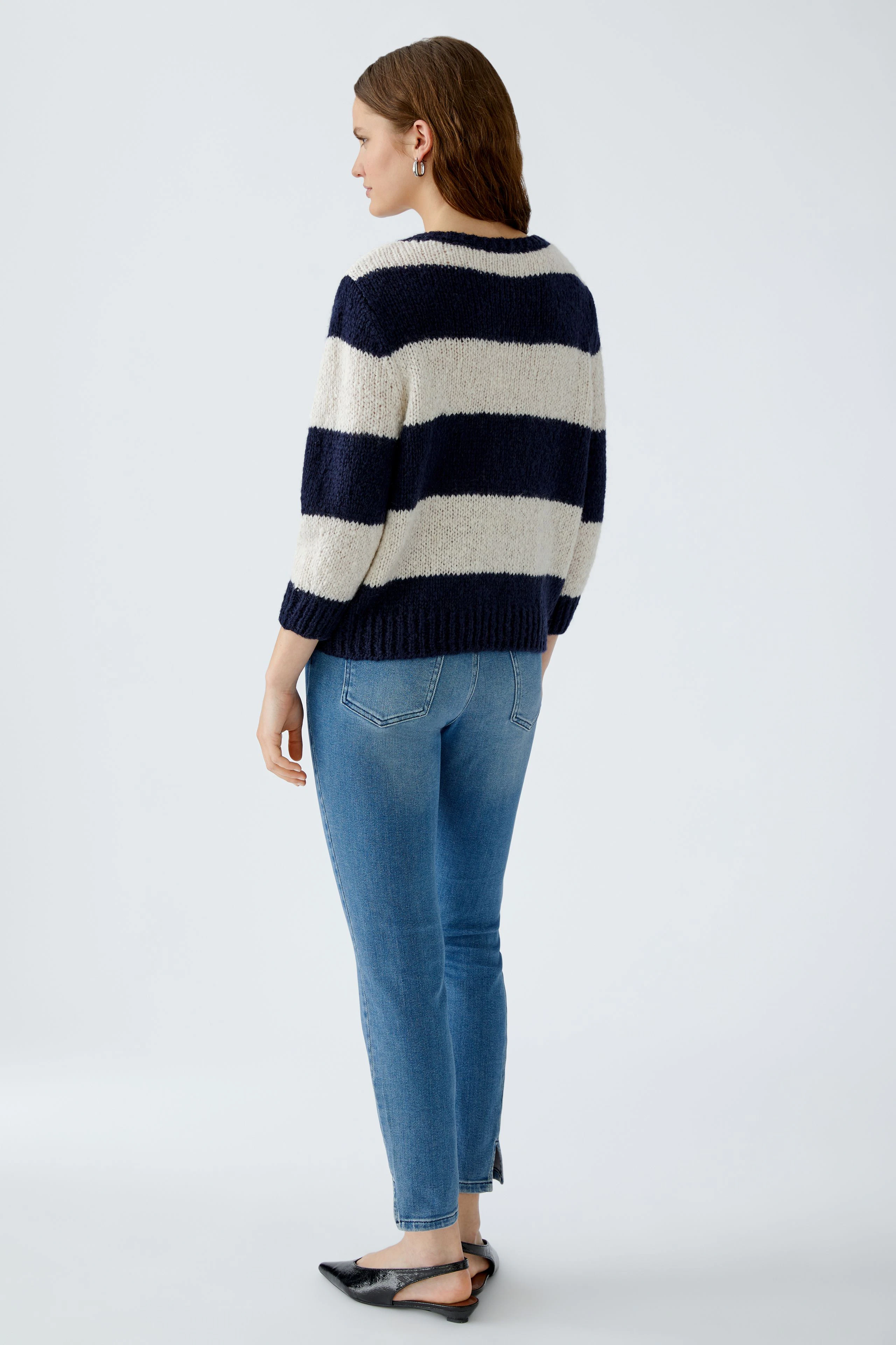 Damen-Pullover: Frau in gestreiftem Pullover mit lockerer Passform und lässigen Jeans von hinten.