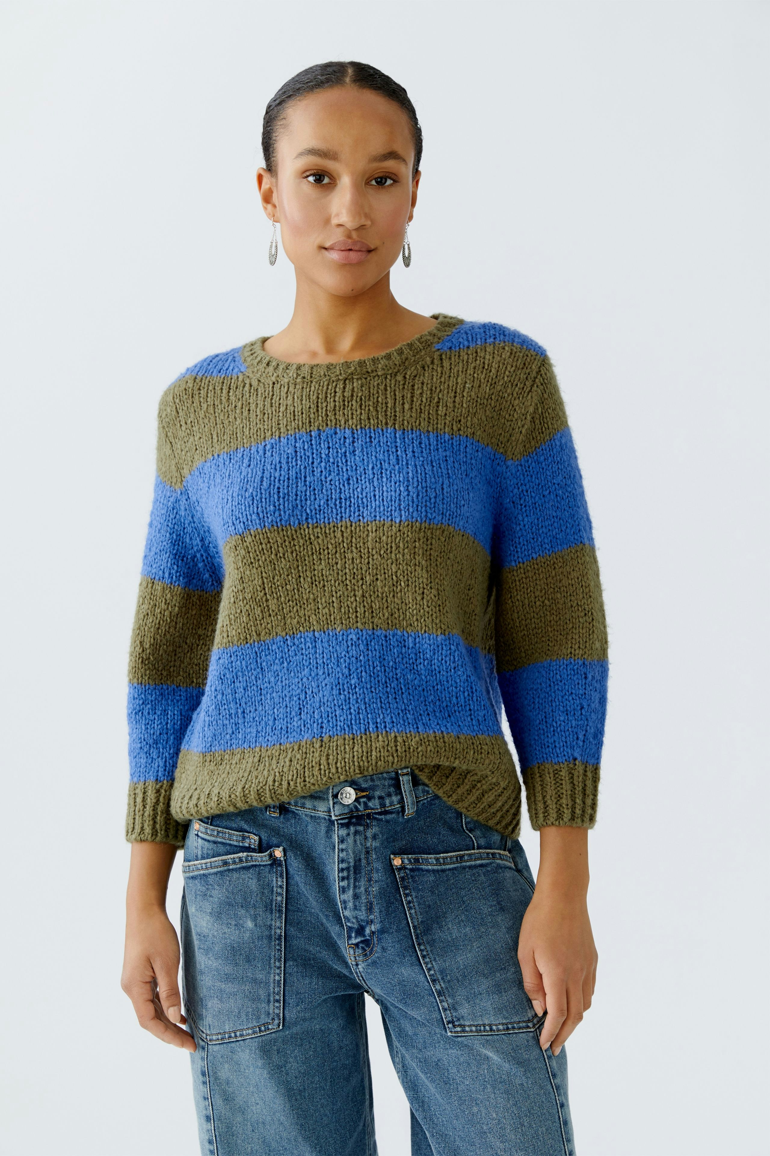Damen-Pullover in grün-blau gestreift, lässig kombiniert mit Jeans, getragen von einer Frau.