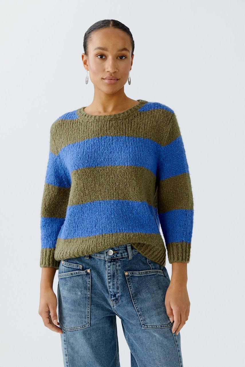 Casual women's pullover: A woman in a striped pullover with blue and green hues, paired with jeans.