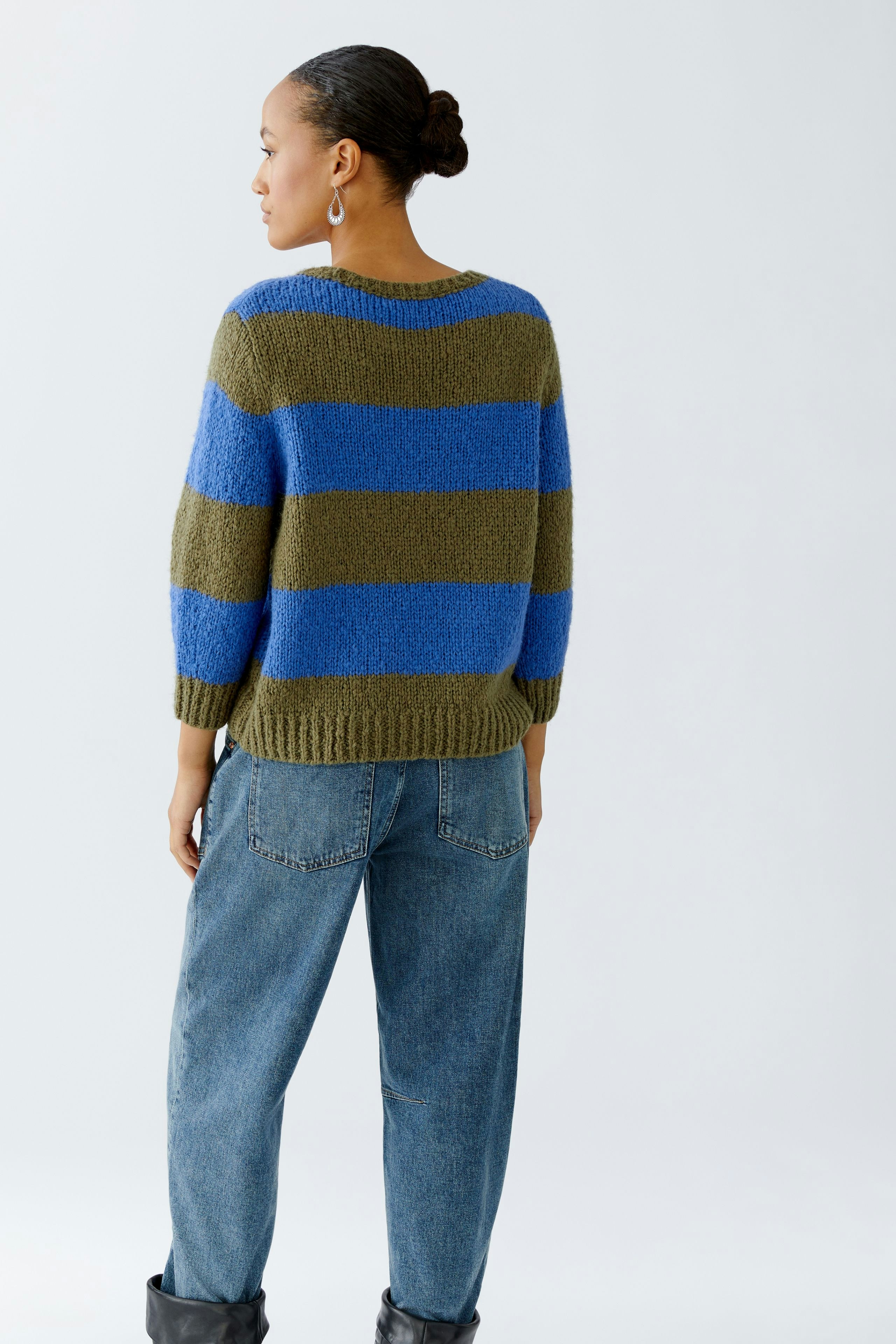Damen-Pullover: Frau trägt einen gestreiften Pullover in Blau und Olivgrün, kombiniert mit lässigen Jeans.