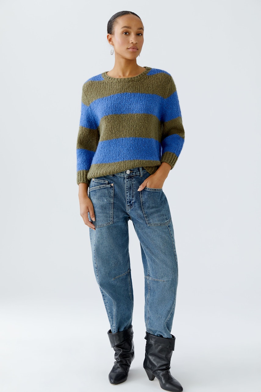 Casual women's pullover: Woman in a striped pullover with blue and green hues, paired with relaxed jeans.