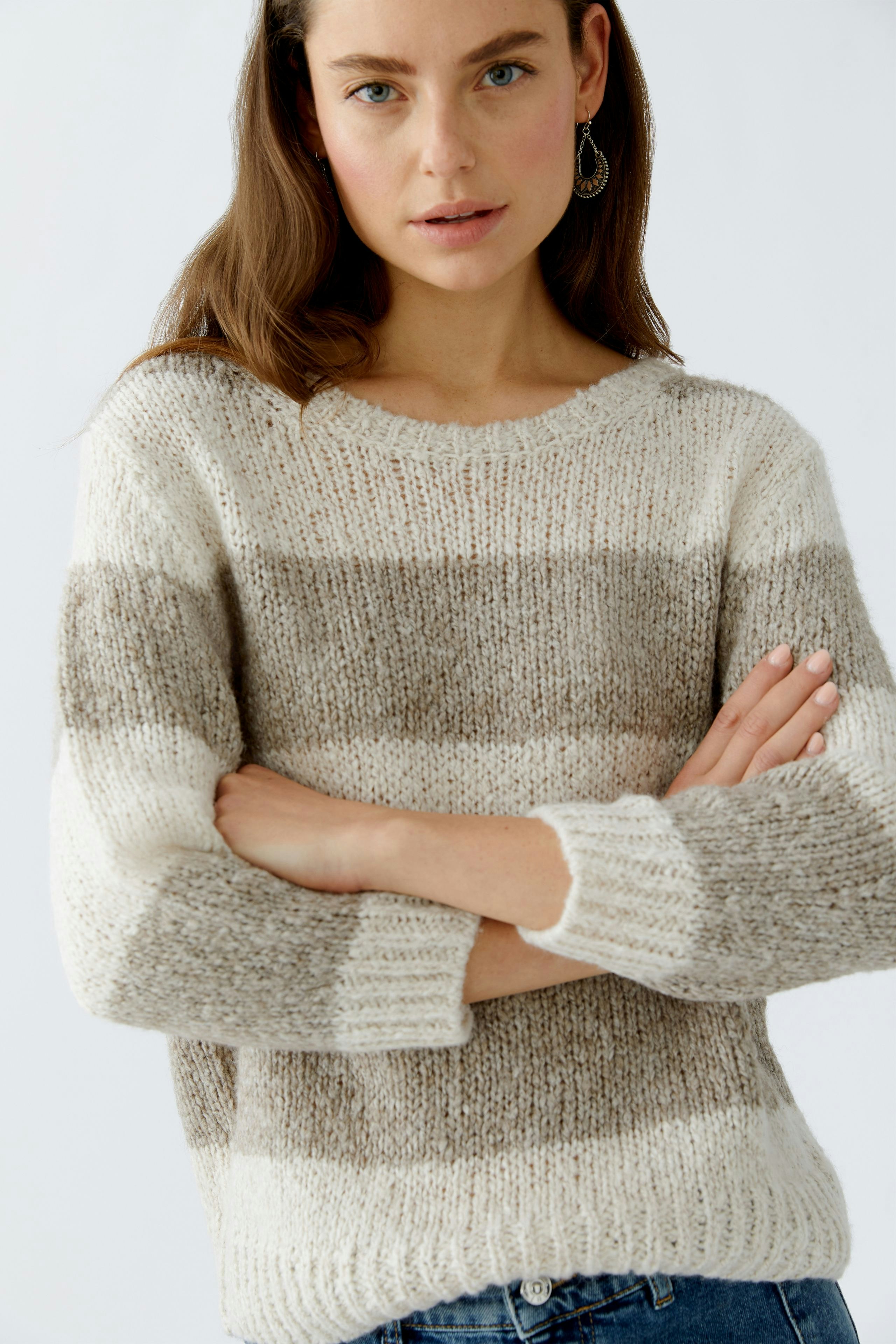 Casual women's pullover: A woman in a striped pullover with neutral tones, arms crossed, looking relaxed.