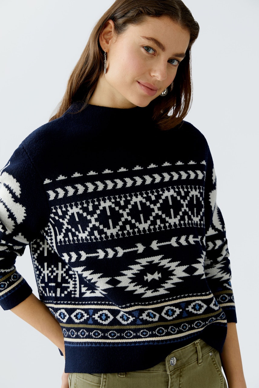 Damen-Pullover: Junge Frau in einem dunkelblauen Pullover mit grafischem Muster und lässigem Schnitt.