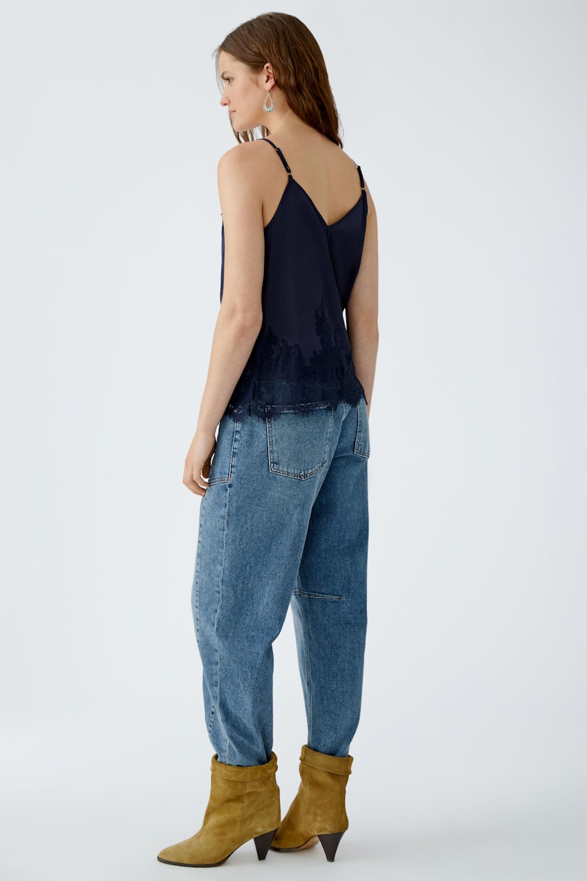 Casual women's top: A woman in a navy tank top with lace details, paired with relaxed jeans and boots.