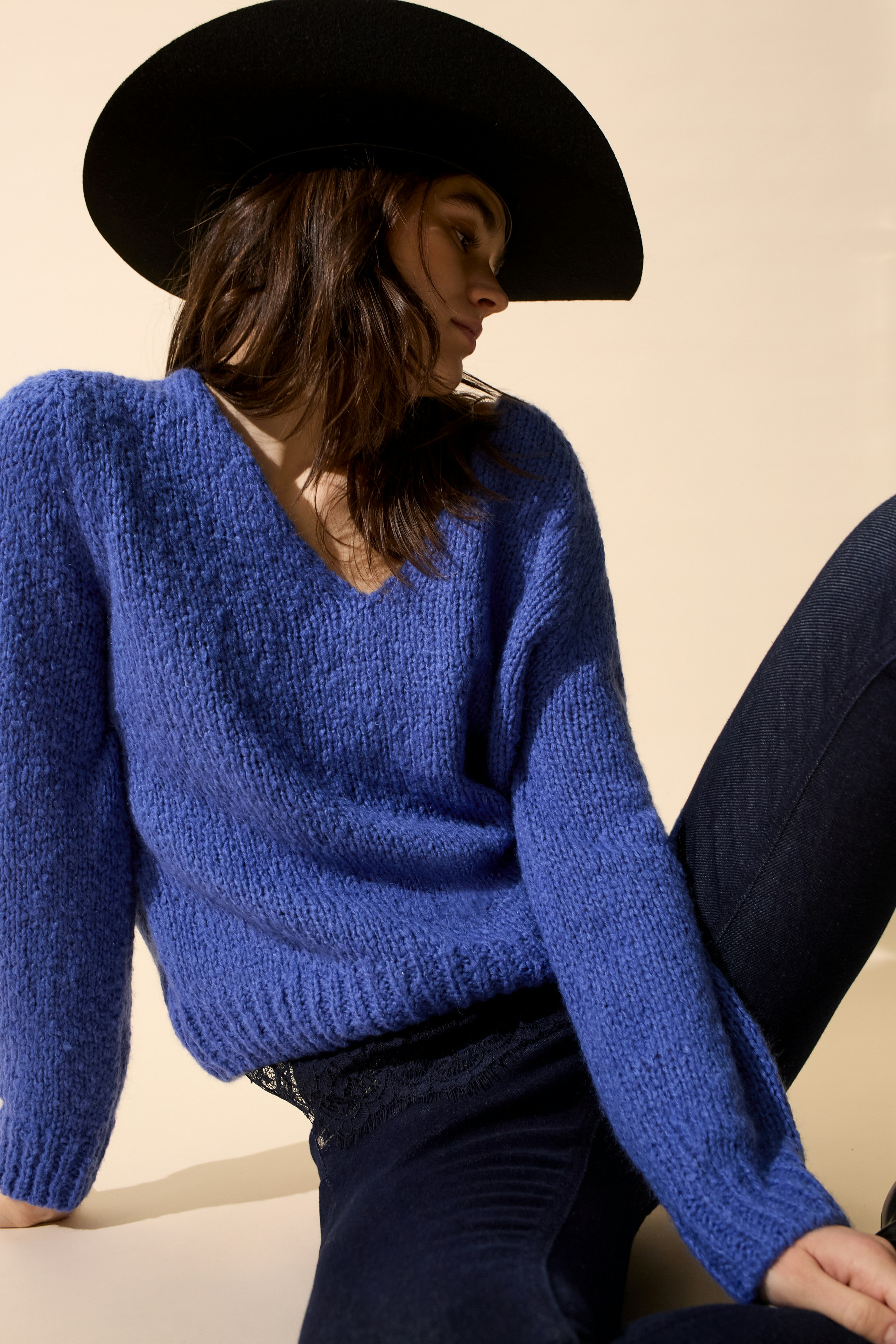 Casual women's pullover: Young woman in a cozy blue knit pullover, paired with dark jeans and a wide-brimmed hat.