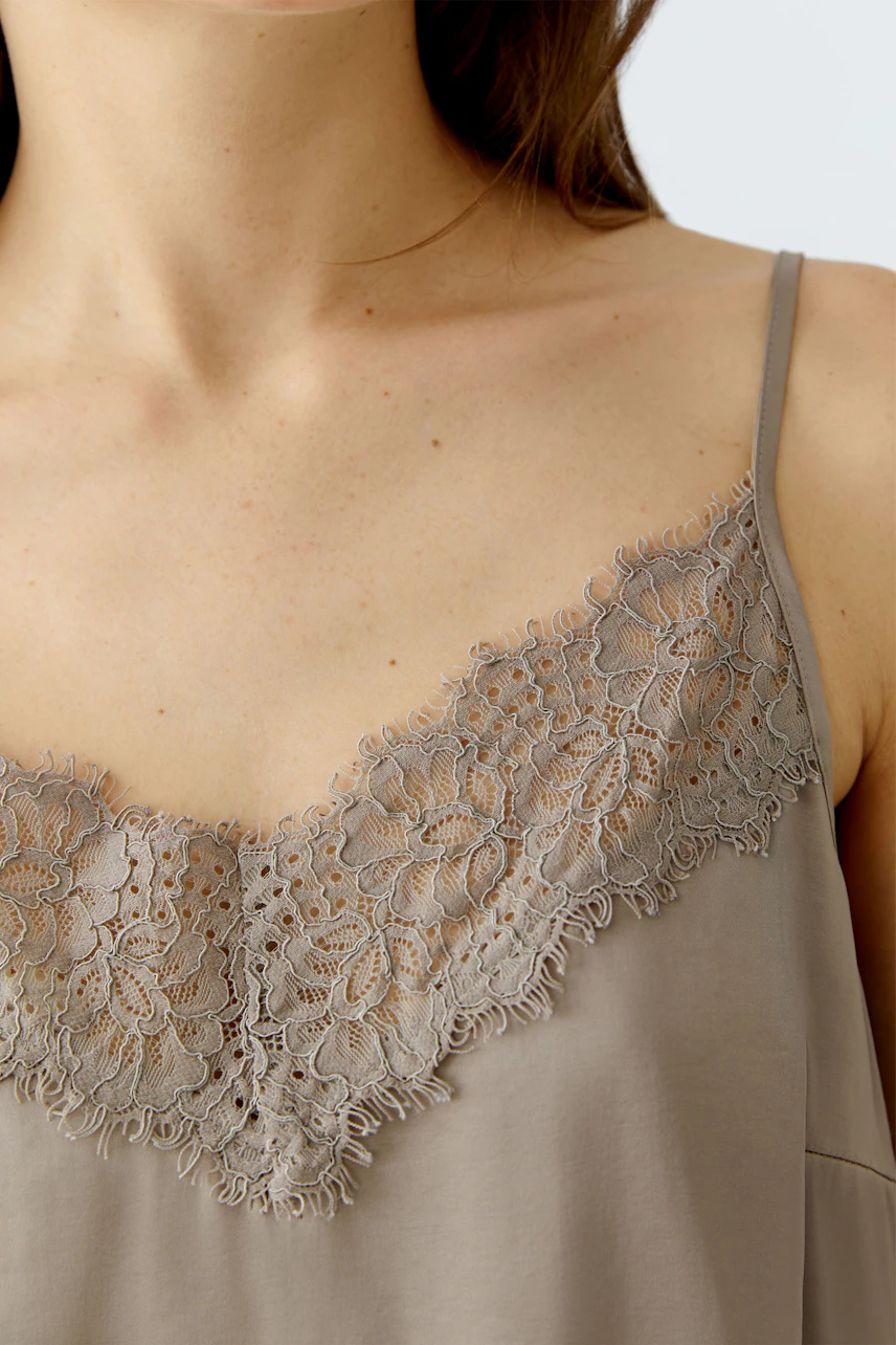 Casual women's top: Close-up of a woman wearing a light brown top with lace detailing.