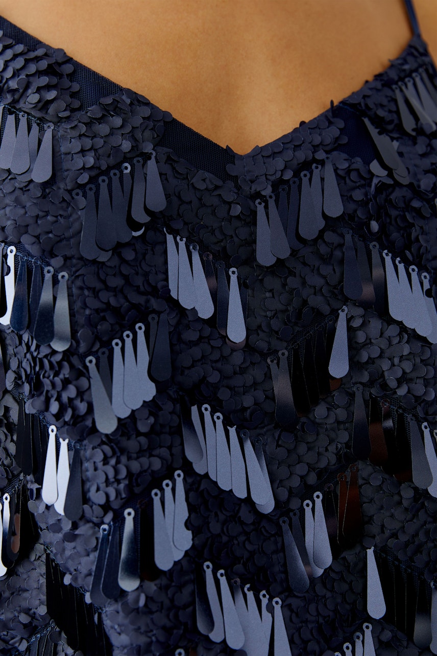 Stylish women's top: Close-up of a woman wearing a navy top with shimmering sequins, perfect for casual outings.