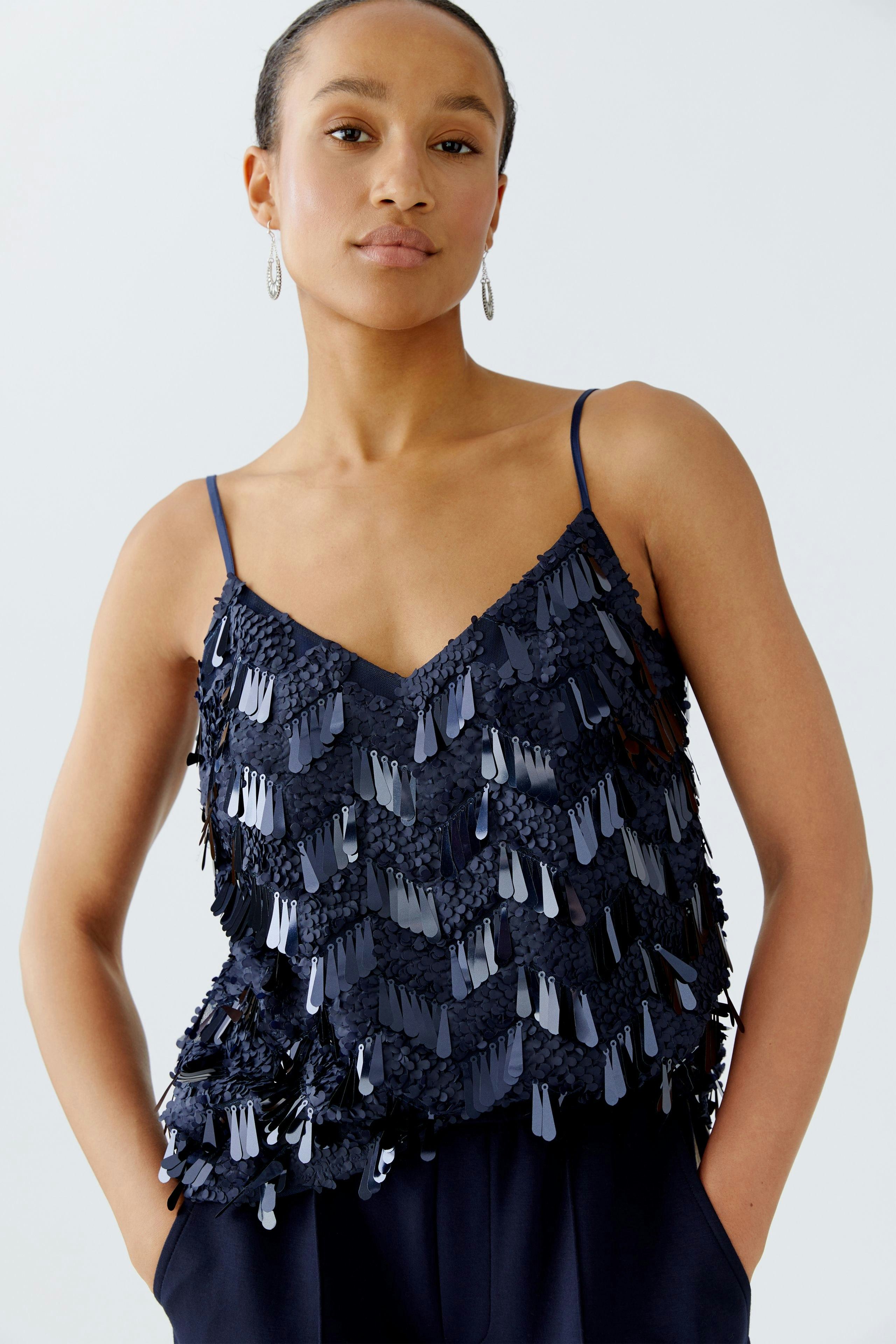 Damen-Top: Junge Frau trägt ein schickes, dunkelblaues Top mit fransigen Details und Spaghettiträgern.
