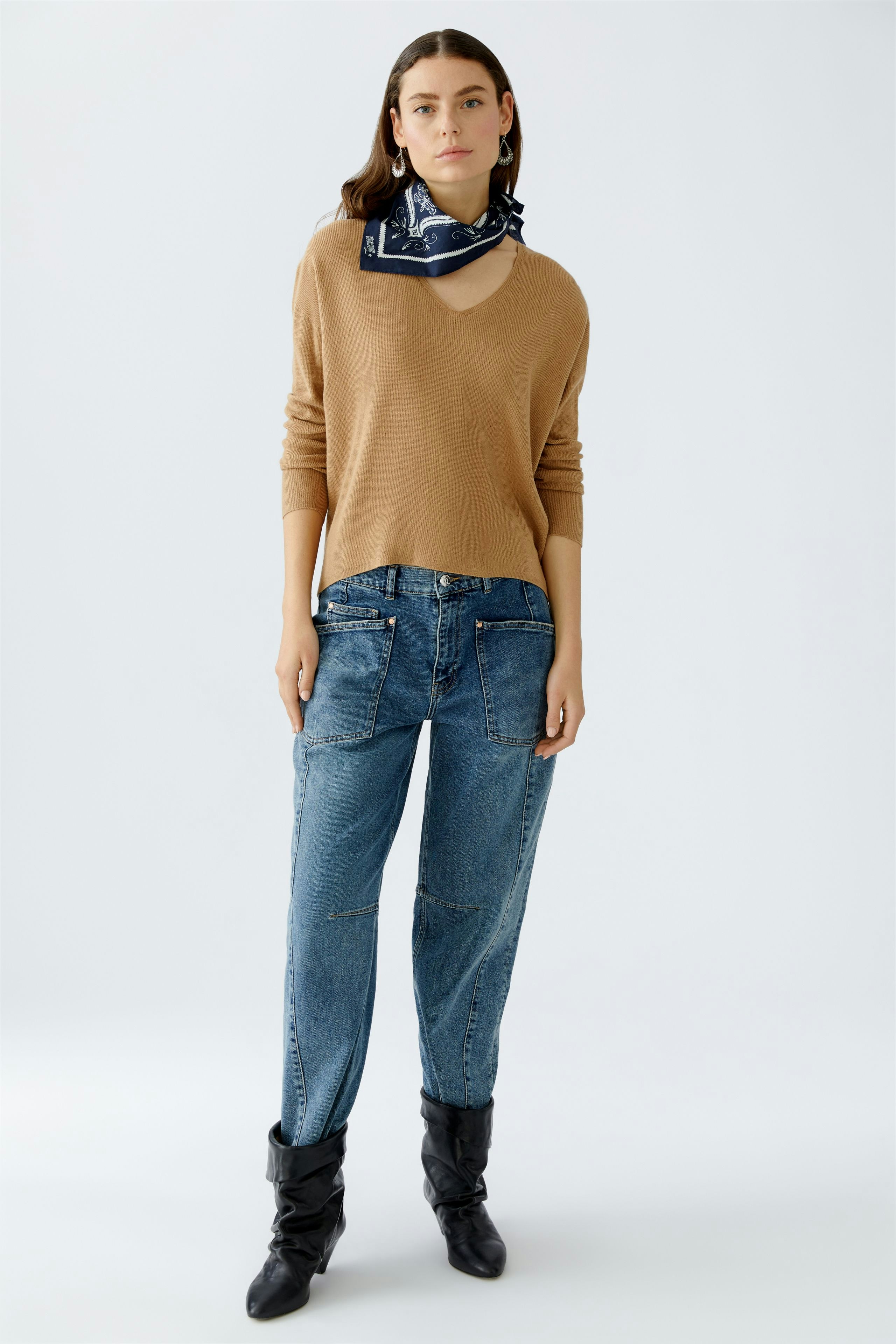 Casual scarf: Woman wearing a stylish scarf with a modern pullover and relaxed jeans.