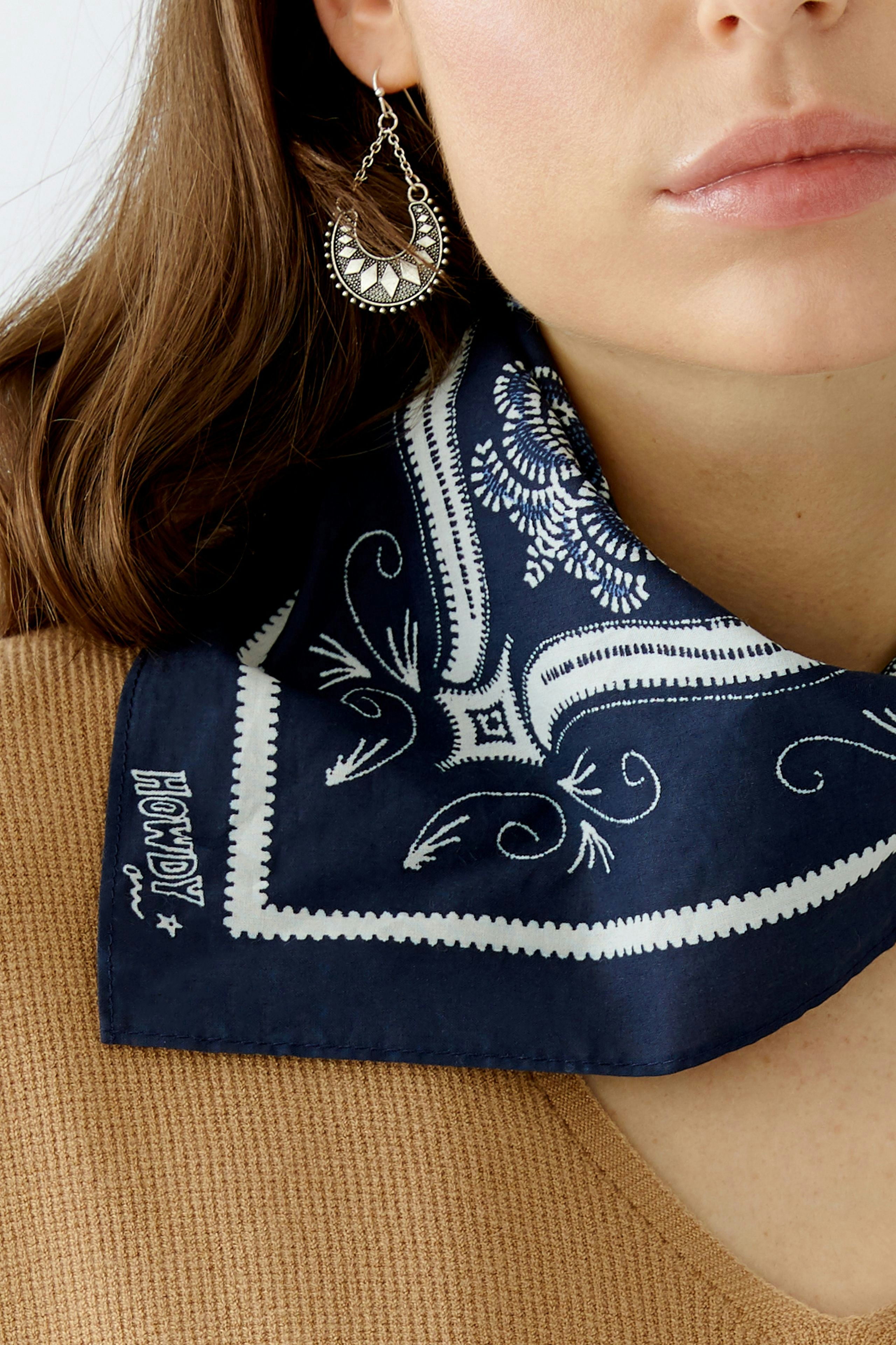 Stylish women's scarf: A woman wears a navy blue scarf with a white pattern, paired with a casual top.
