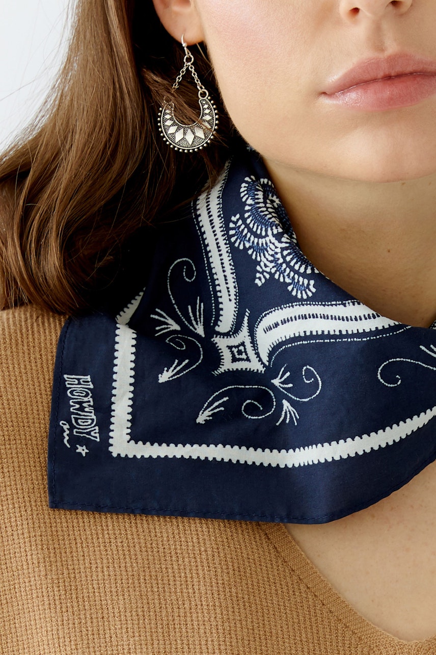 Stylish women's scarf: A woman wears a navy blue scarf with a white pattern, paired with a casual top.
