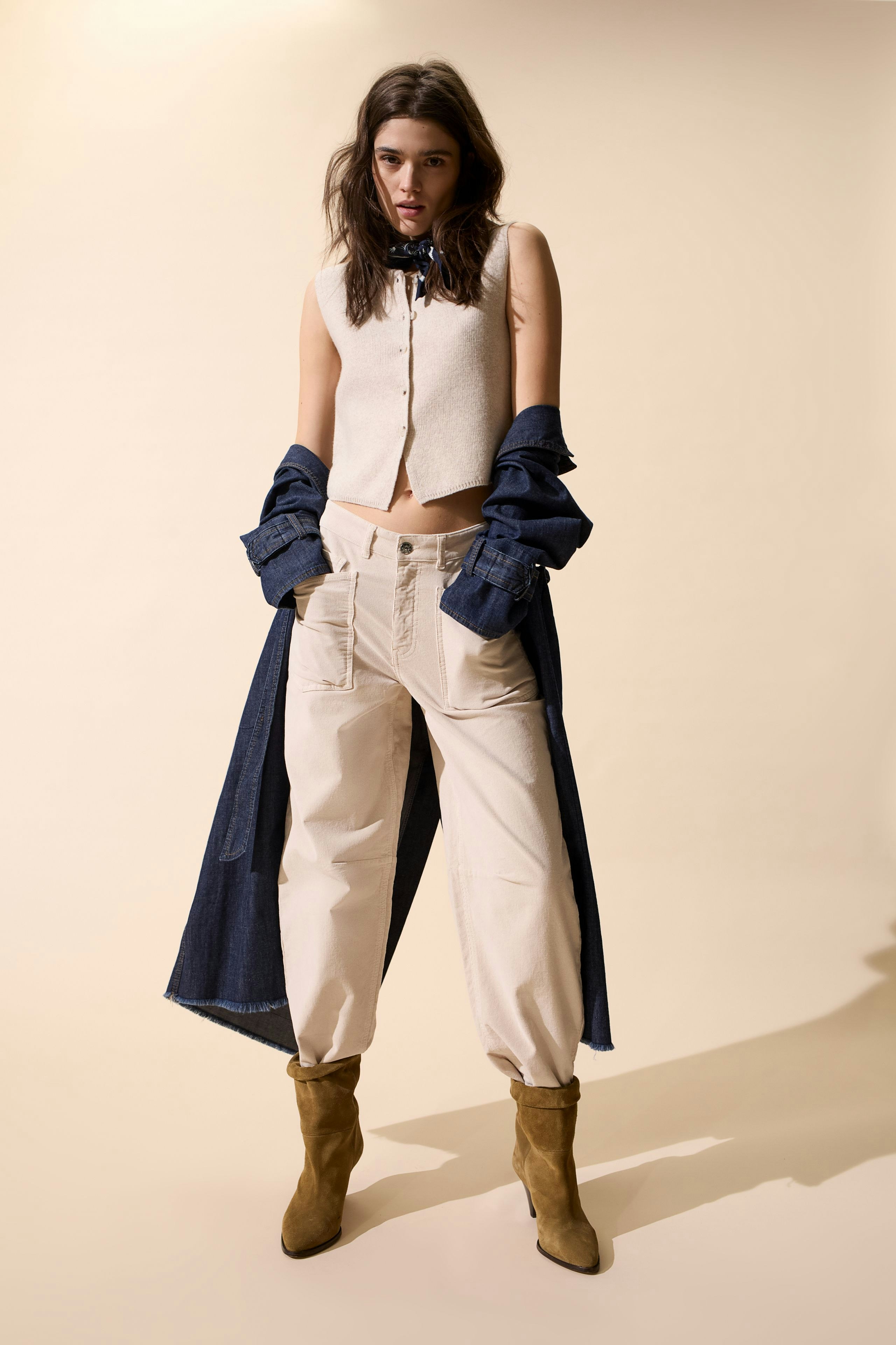 Casual women's scarf: A woman in a light scarf layered over a denim shirt and relaxed pants.