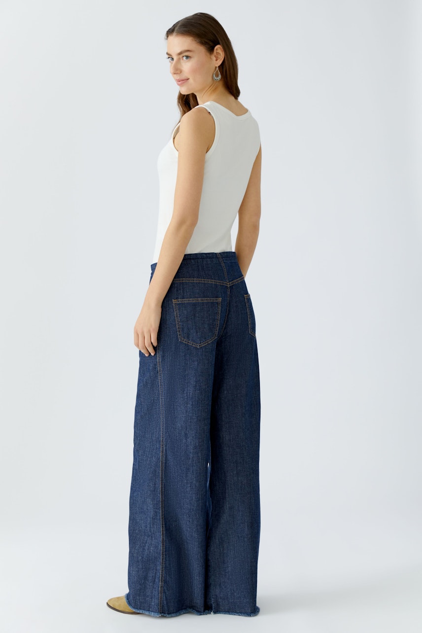 Wide leg jeans on a woman, featuring a relaxed fit and classic dark denim design.
