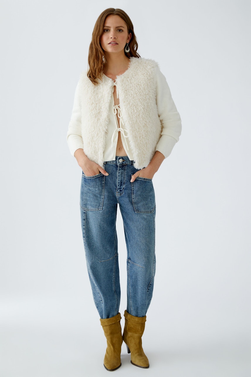 Casual women's jeans: A woman in relaxed-fit barrel jeans paired with a cozy white vest.