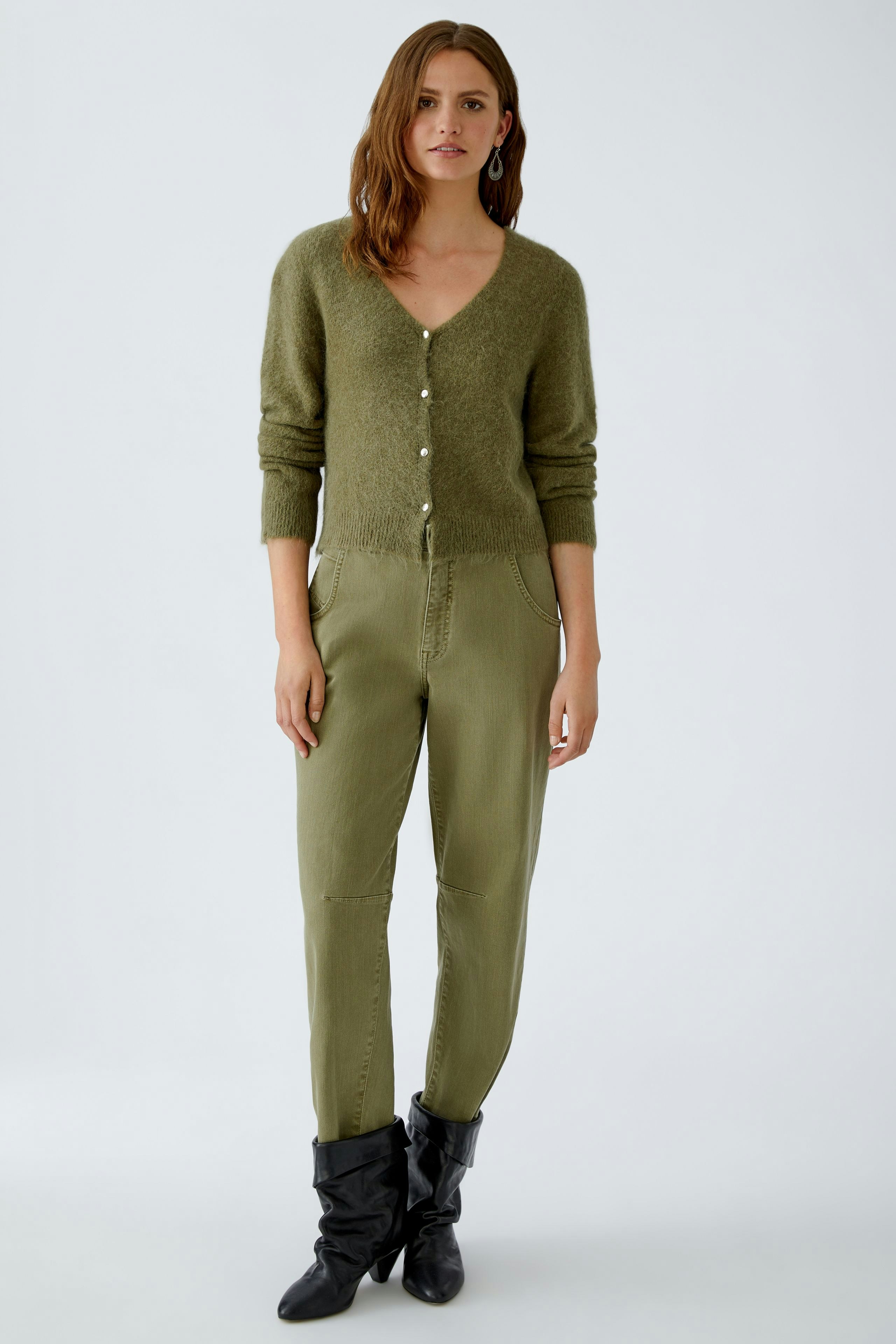 Casual women's jeans: A woman in olive green barrel jeans paired with a soft cardigan.