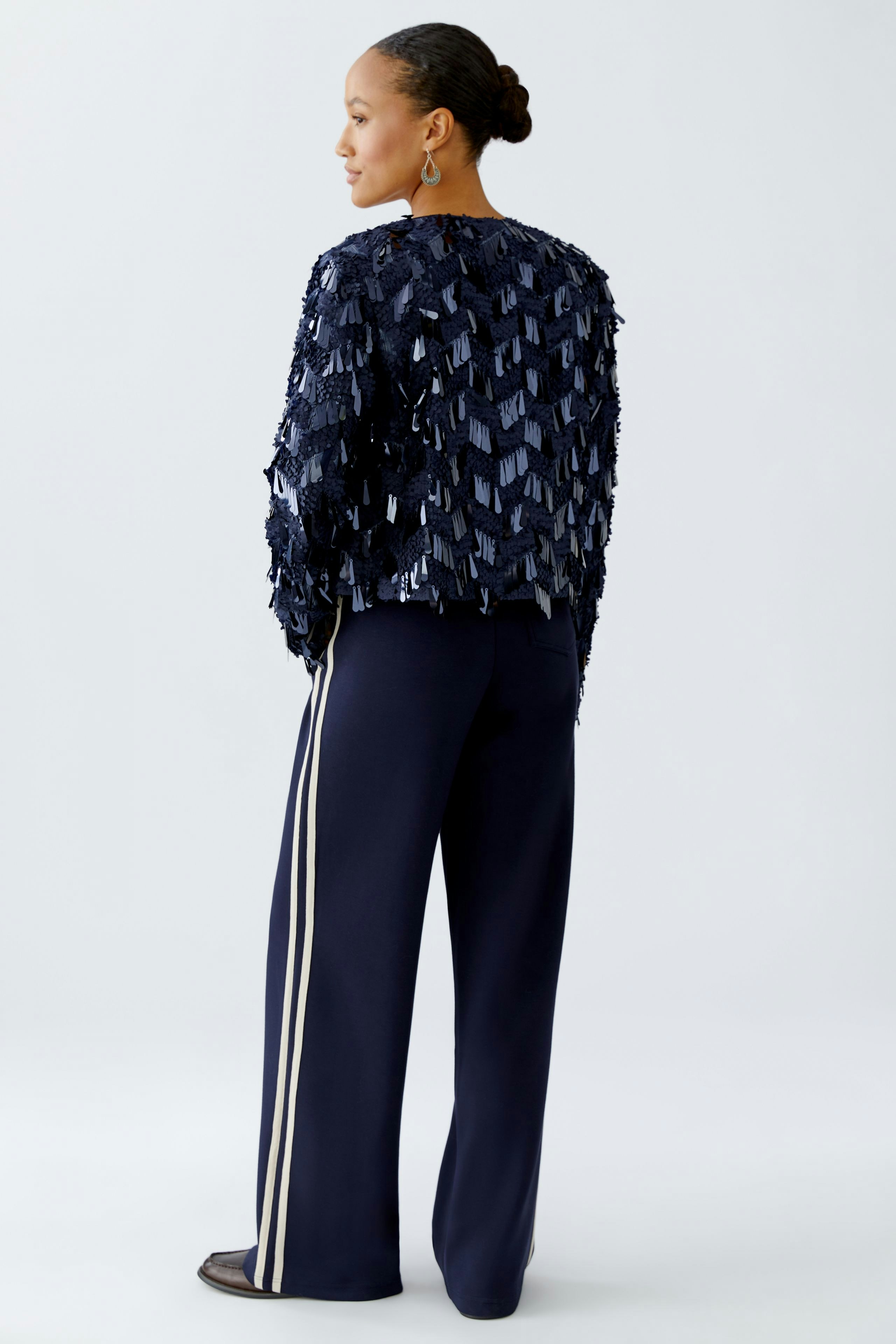 Stylish women's jacket: A woman in a navy jacket with textured details and sporty pants.