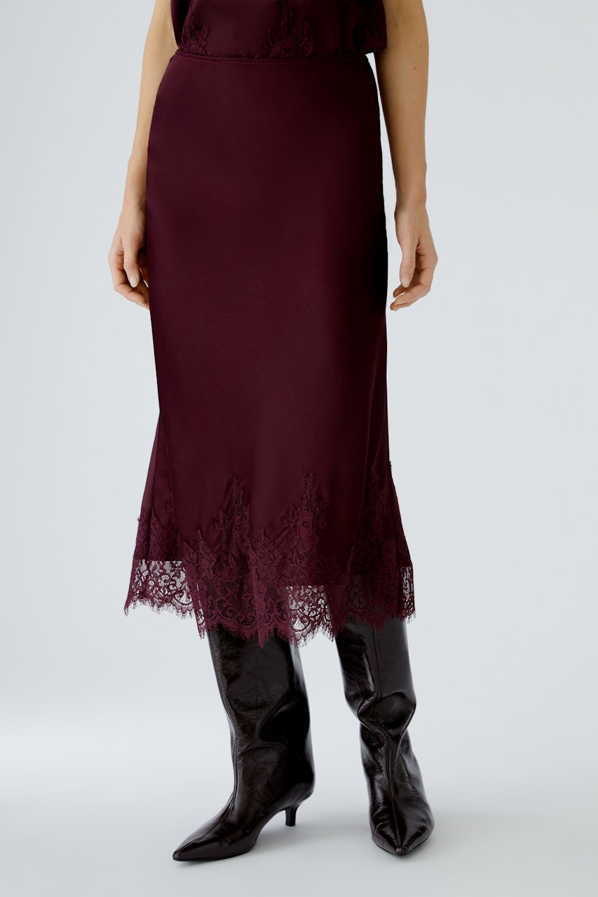 A-line skirt: Woman in a burgundy skirt with lace trim, paired with stylish knee-high boots.