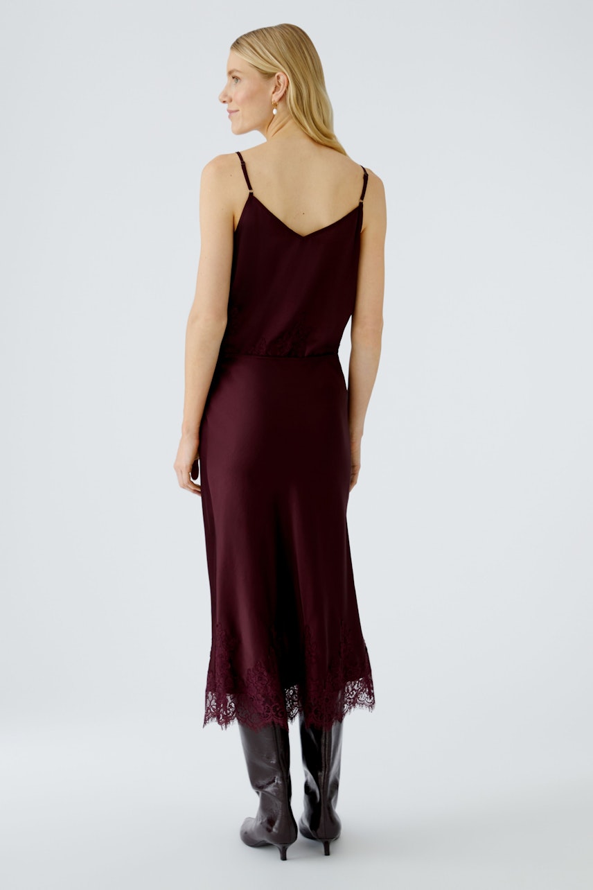 A-line skirt: Woman in a burgundy dress with lace hem, paired with stylish knee-high boots.