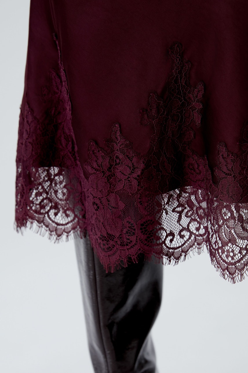 A-line skirt: A woman showcases a burgundy skirt with delicate lace trim, perfect for casual wear.