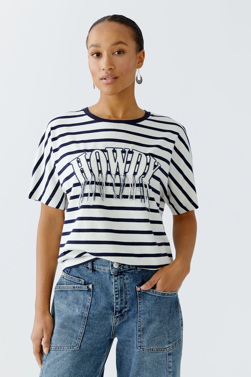 Lässiges Damen-T-Shirt: Frau in gestreiftem Shirt mit Aufdruck und lockeren Jeans.
