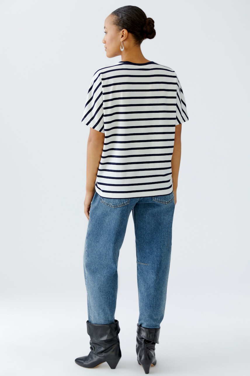 Damen-T-Shirt: Frau trägt ein gestreiftes T-Shirt mit kurzen Ärmeln und lässigen Jeans.