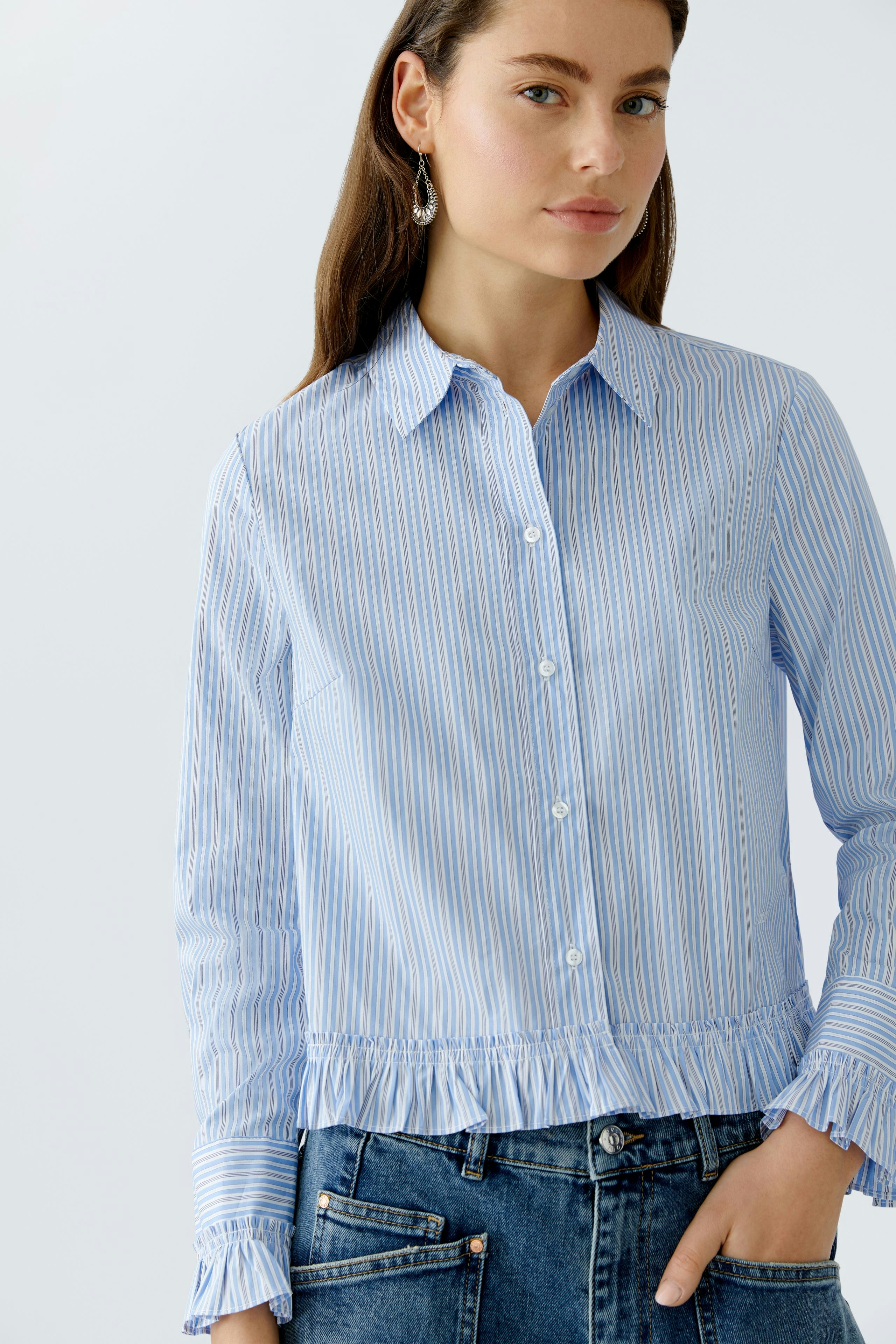 Casual women's blouse: A woman in a light blue striped blouse with a ruffled hem and button closure.