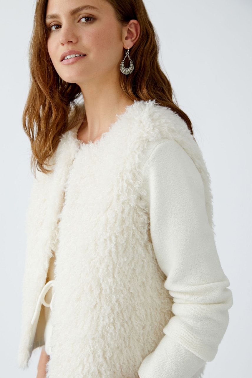 Cozy women's vest: A woman in a fluffy, pink and white knitted vest, showcasing a relaxed style.
