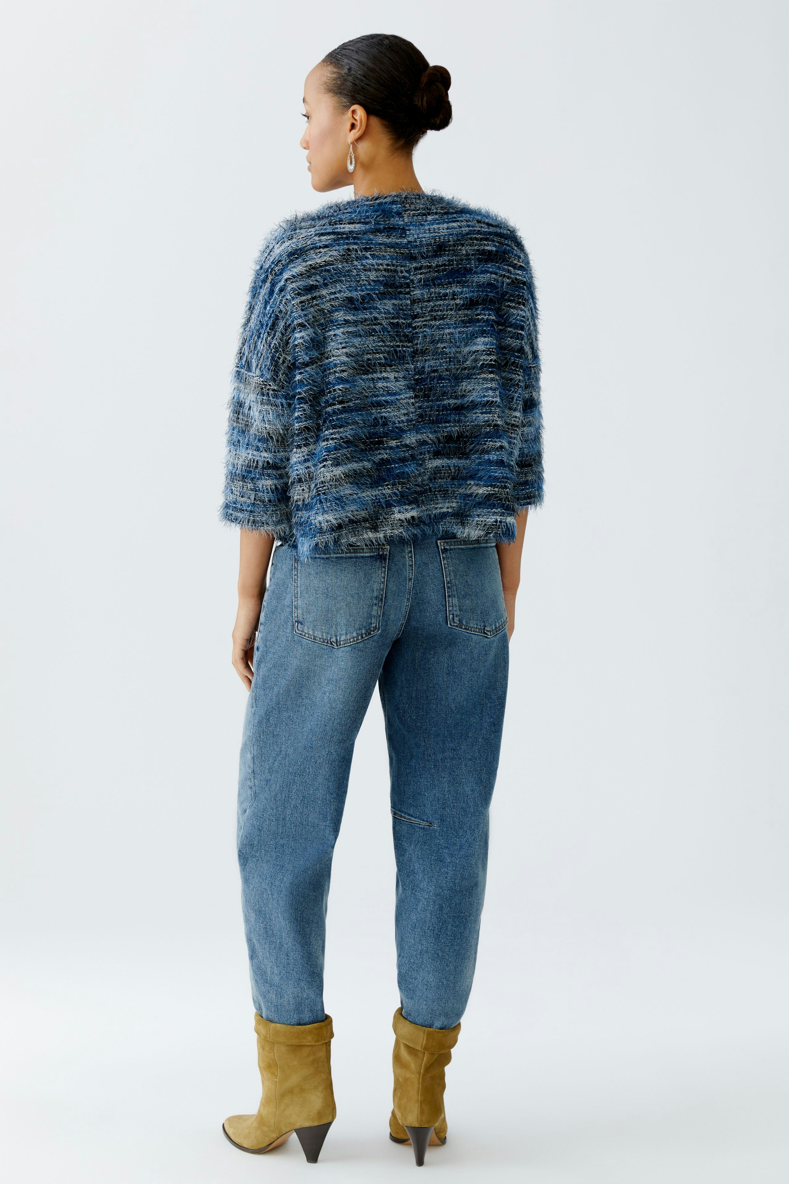 Casual women's pullover: A woman in a cozy blue knit pullover paired with relaxed jeans.