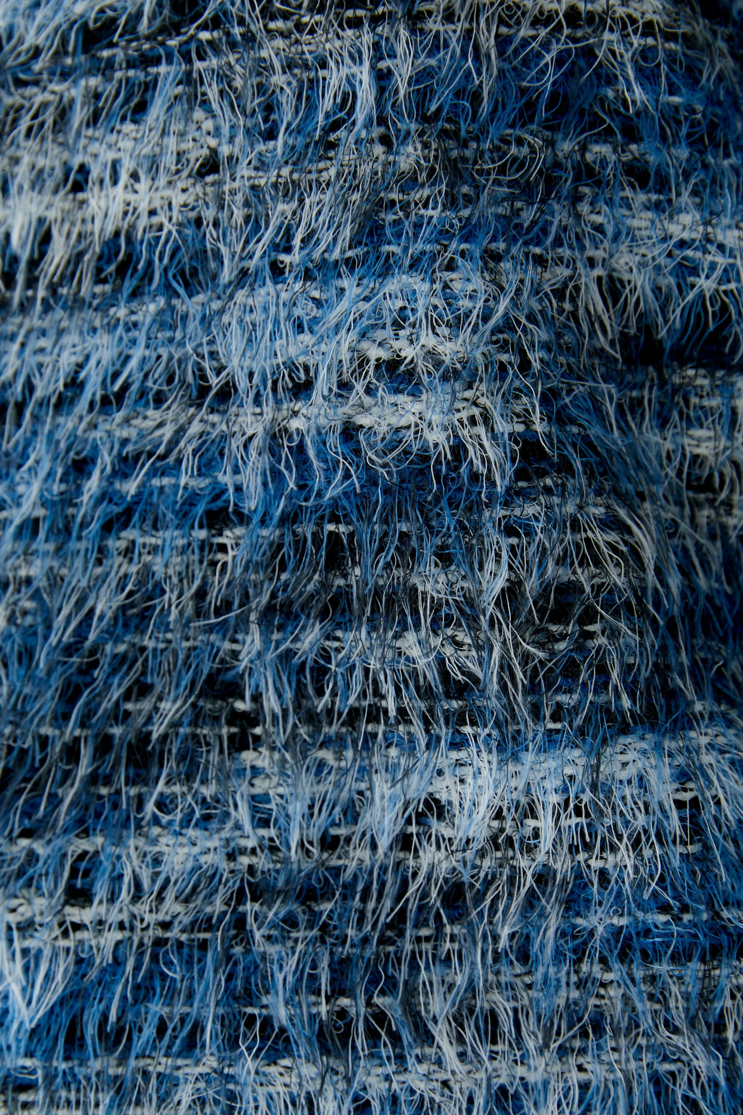Textured blue pullover: Close-up of a women's pullover with a unique, fuzzy design in various blue shades.