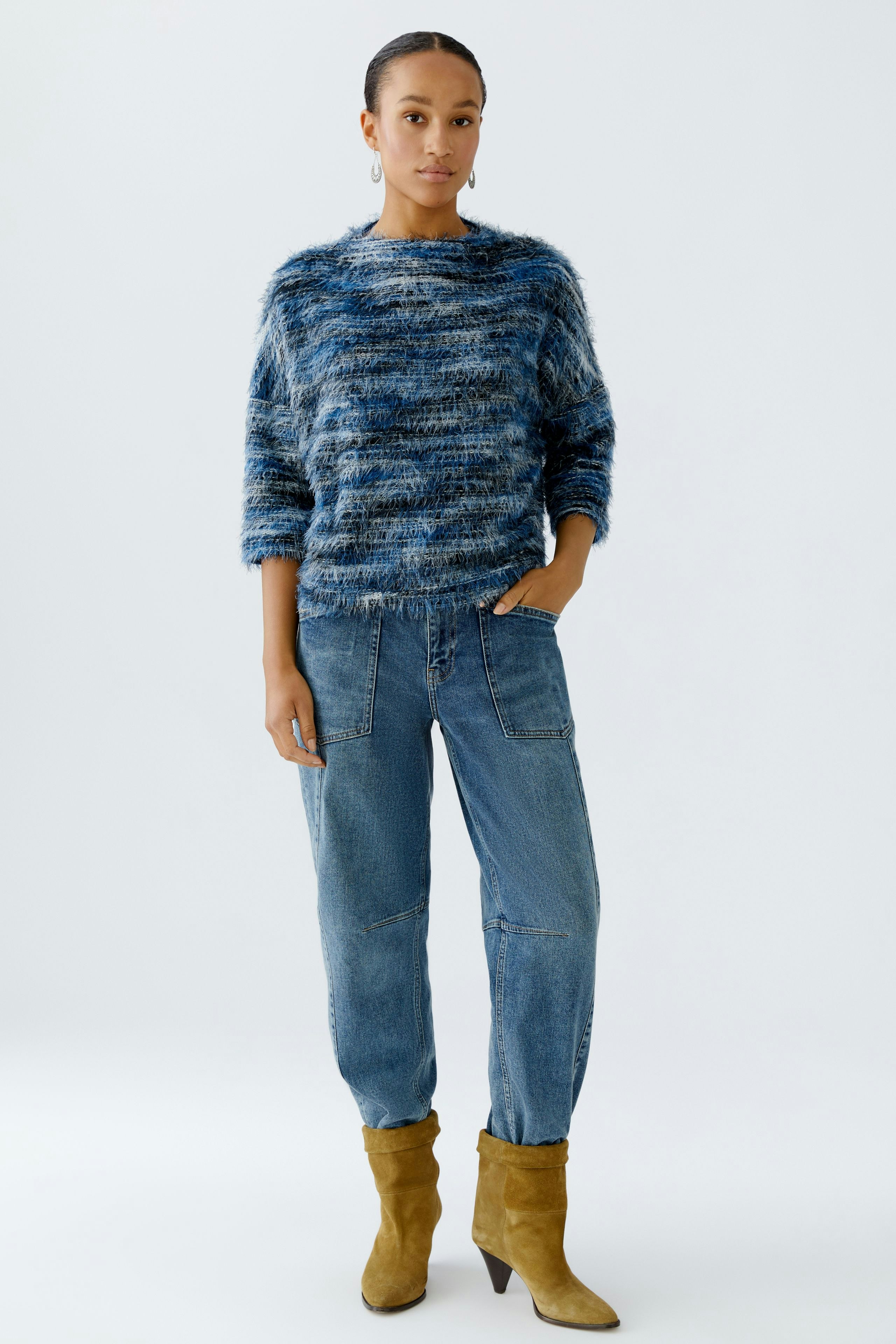 Casual women's pullover: Young woman in a blue fuzzy pullover paired with relaxed jeans.