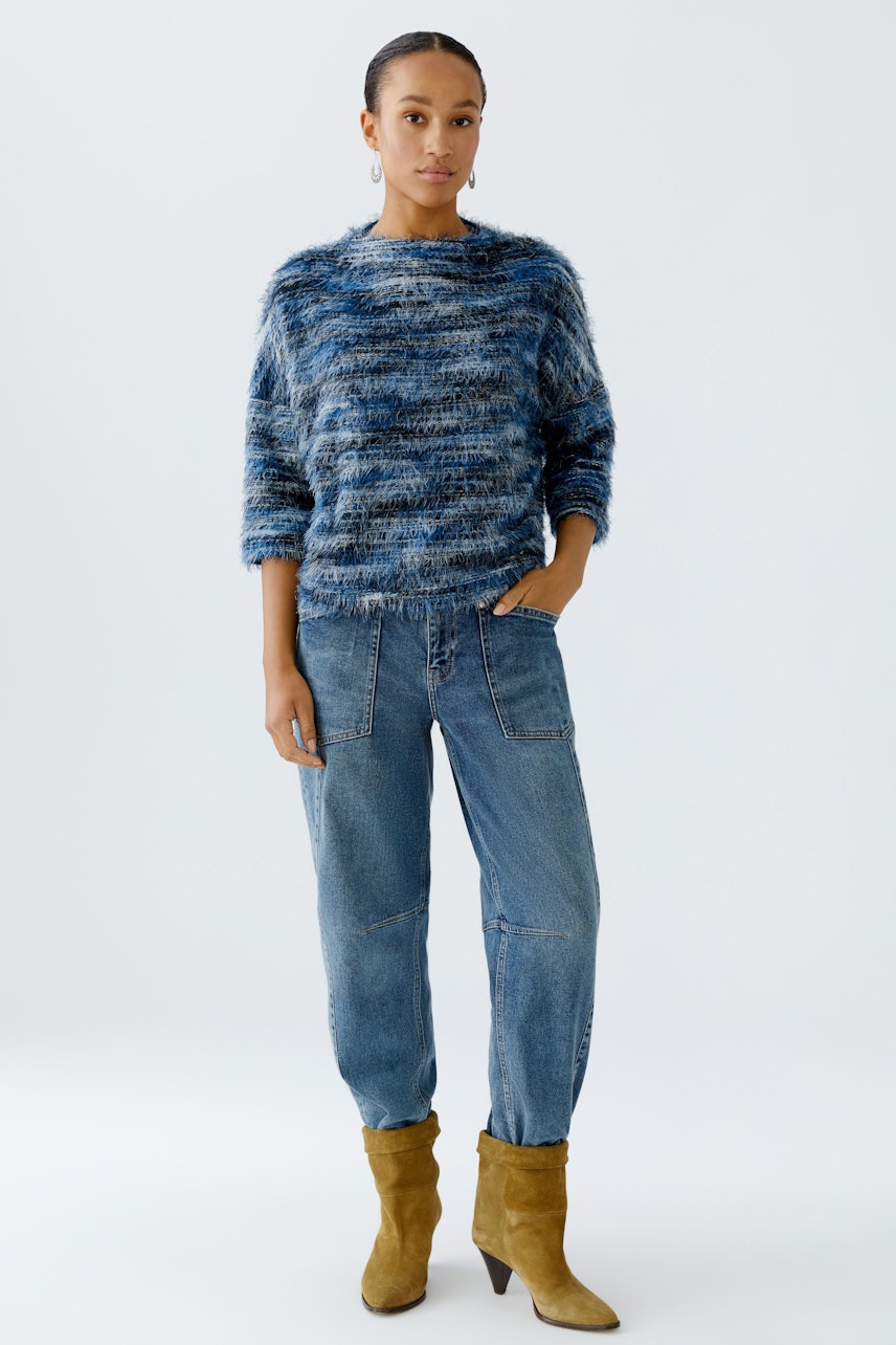 Casual women's pullover: Young woman in a blue fuzzy pullover paired with relaxed jeans.