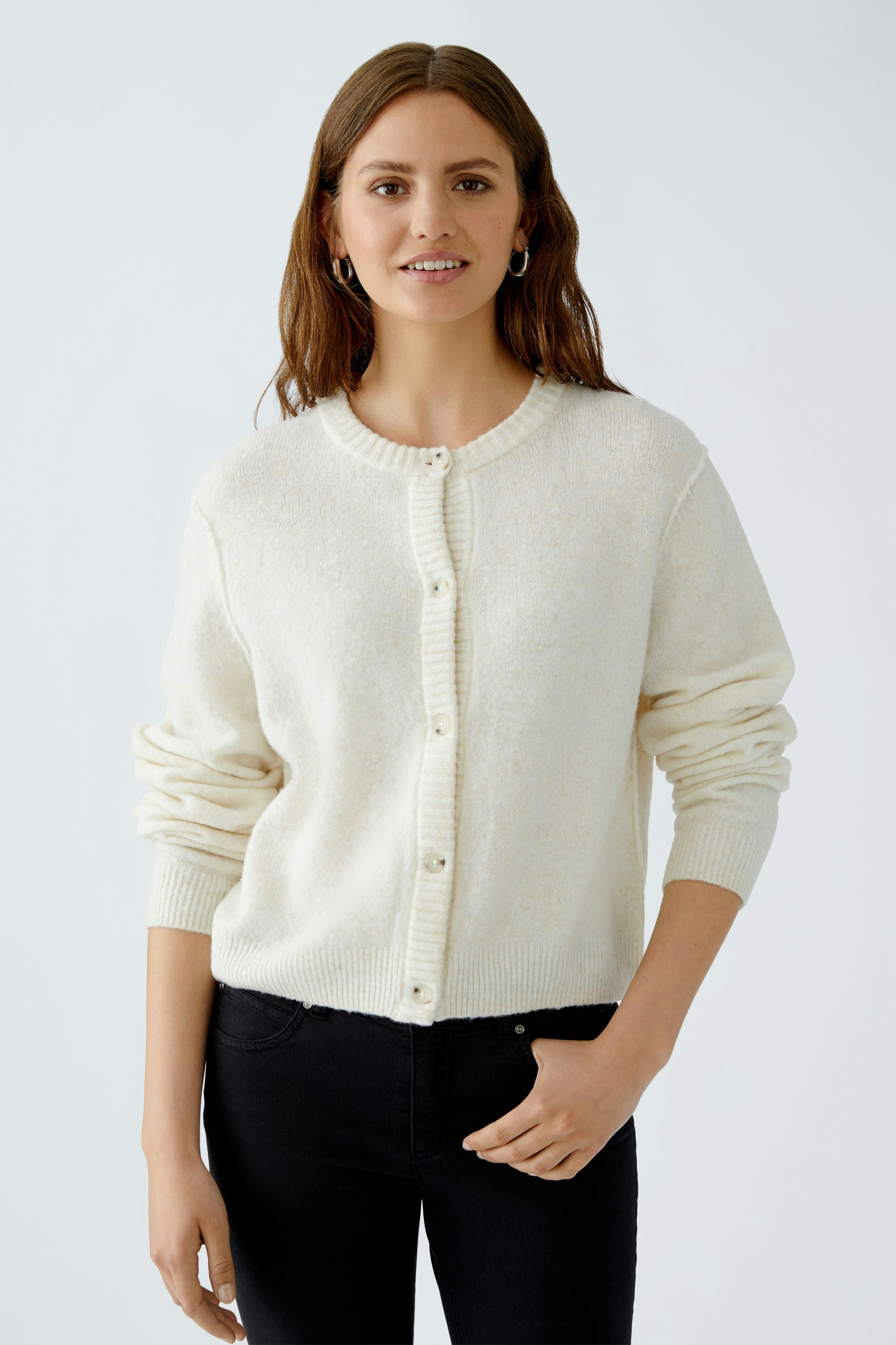 Bequeme Damen-Strickjacke: Frau in cremefarbener Strickjacke mit Knöpfen und lässigem Look.