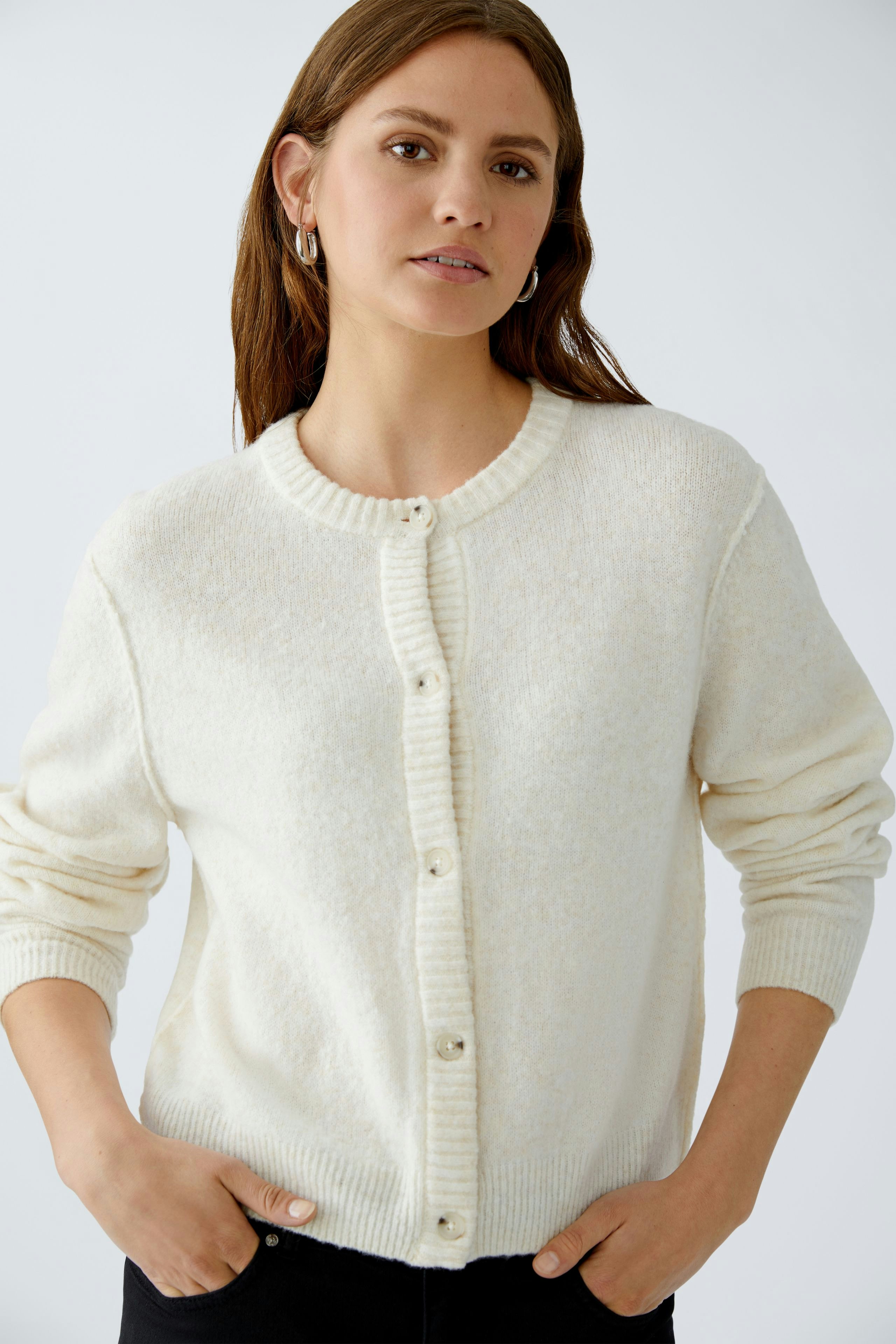 Bequeme Damen-Strickjacke: Frau in cremefarbener Strickjacke mit Knöpfen und lässigem Look.