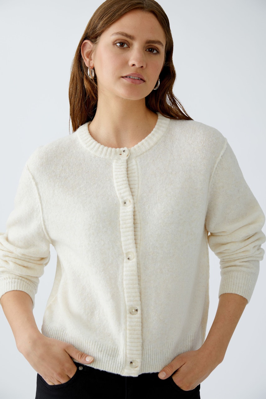 Casual women's cardigan: A woman in a soft white cardigan with buttons, perfect for layering.
